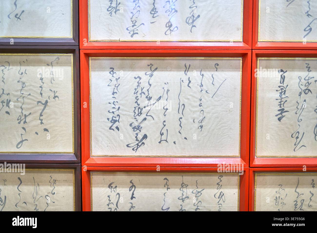 Eine Nahaufnahme einer rasterartigen Anordnung von gerahmten traditionellen japanischen Kalligrafiekunstwerken, die an einer Wand angebracht sind. Das Bild zeigt mehrere rechteckige Stockfoto