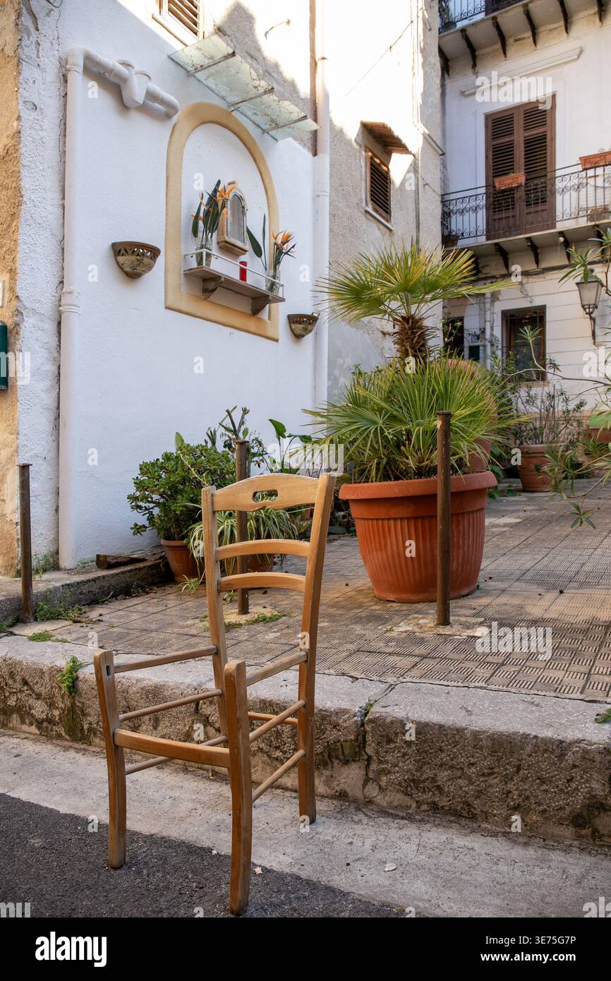 Charmante, ruhige Gasse in einem historischen Dorf in Sizilien mit weiß getünchten Stuckwänden, einer kleinen dekorativen Schrein-Nische und Terrakotta-Topfpflanzen Stockfoto