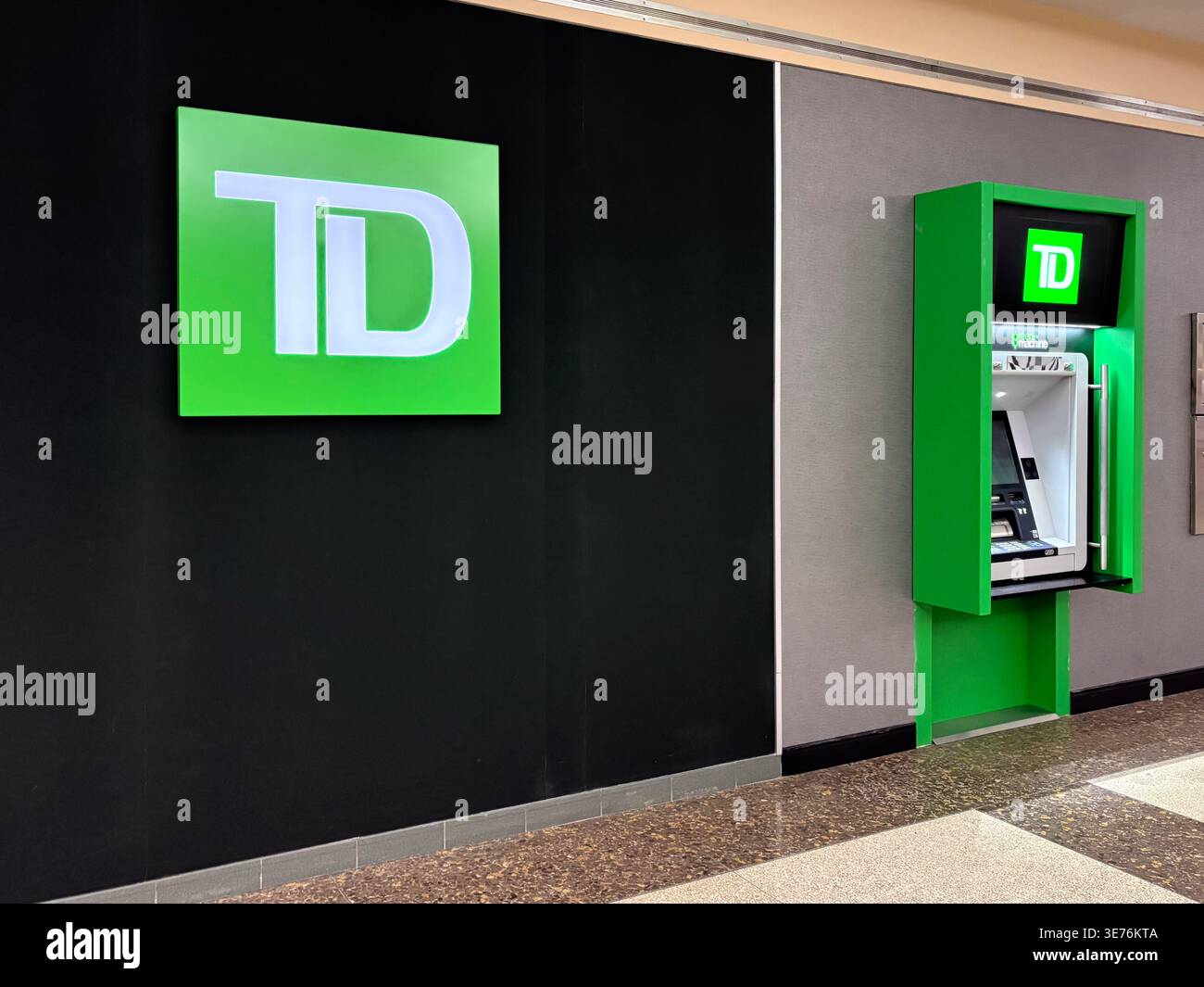 Eine Filialwand der Toronto-Dominion Bank mit dem beleuchteten TD-Markenlogo und einem integrierten Green Machine ATM Kiosk in einem öffentlichen Innenraum. Stockfoto
