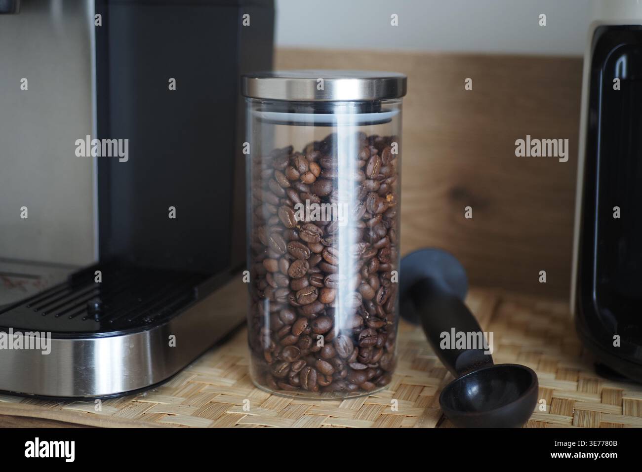 Kaffeebohnen in einem Glas neben einer Kaffeemaschine auf der Theke Stockfoto