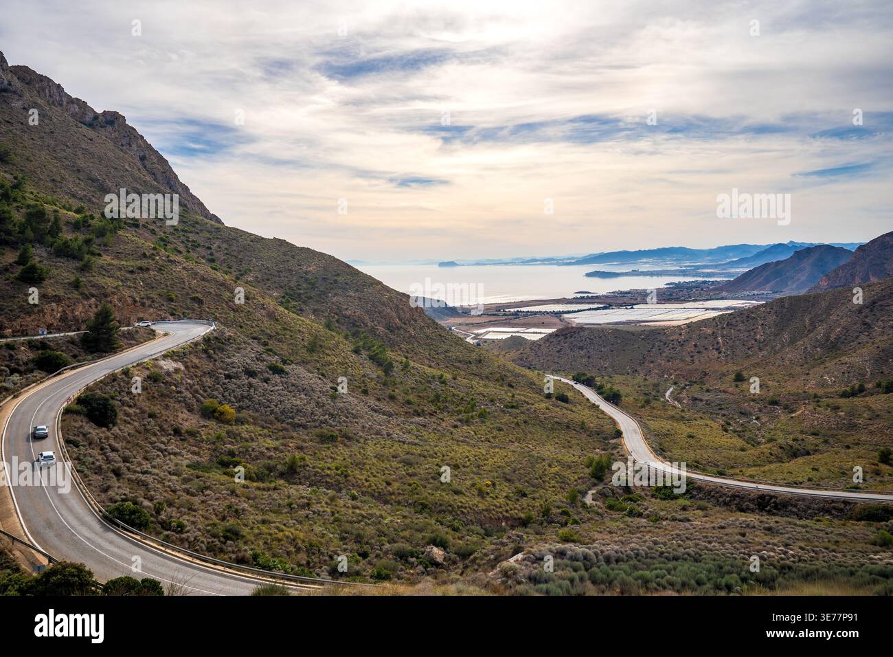Eine gewundene Straße schlängelt sich durch die trockenen Berge der Sierra de la Muela in Richtung Meer. Die aussicht fängt die wilde Schönheit der Costa Calida in der Nähe von Cartagena ein, Stockfoto