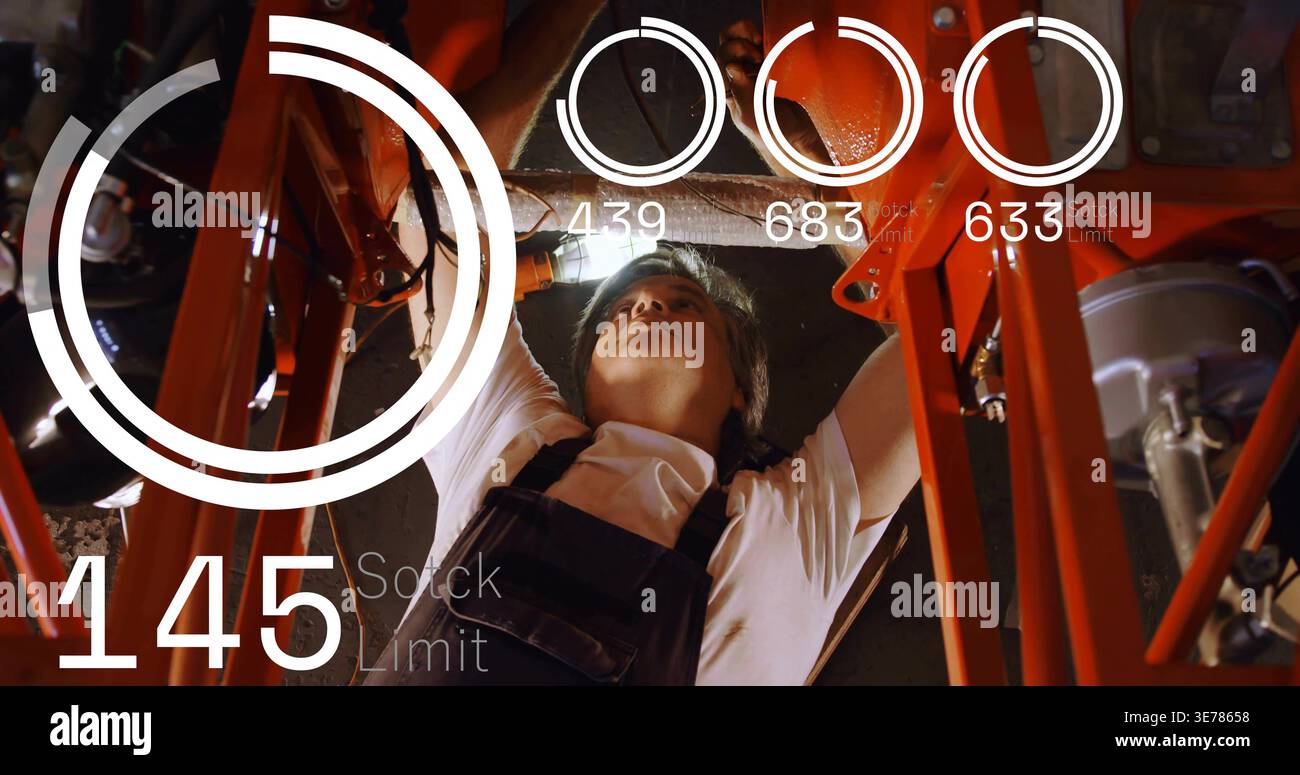 Mechaniker unter rotem Fahrgestell, der auf HUD-Lagerwarnung reagiert und Autoteile mit Brenner inspiziert Stockfoto