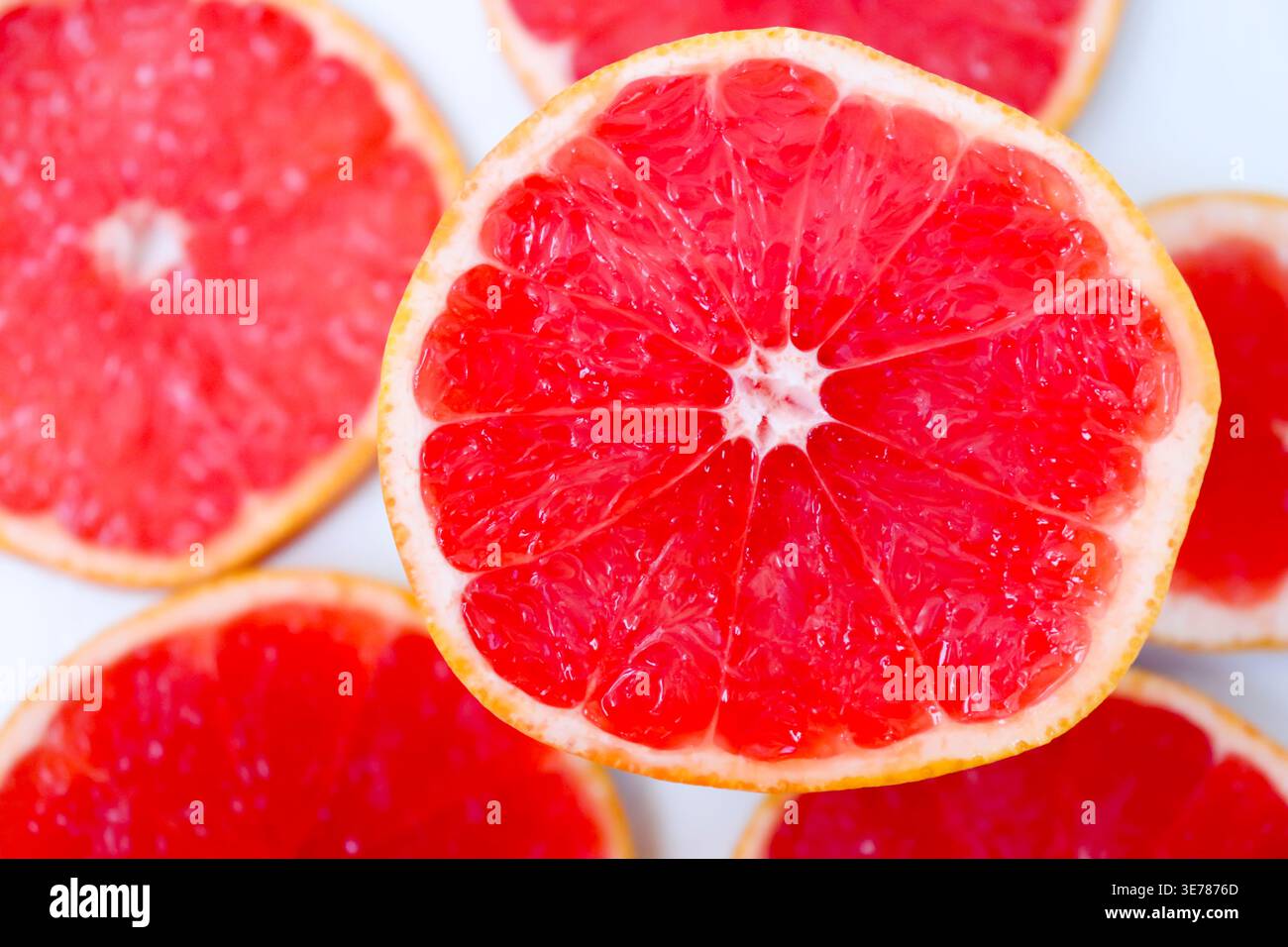 Frisch geschnittene Grapefruitscheiben isoliert auf weißem Hintergrund, knallige rosa oder rote Zitrusfruchtstücke mit saftiger Textur, gesundes natürliches Lebensmittelkonzept. Stockfoto