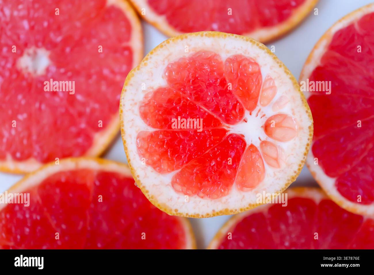 Frisch geschnittene Grapefruitscheiben isoliert auf weißem Hintergrund, knallige rosa oder rote Zitrusfruchtstücke mit saftiger Textur, gesundes natürliches Lebensmittelkonzept. Stockfoto