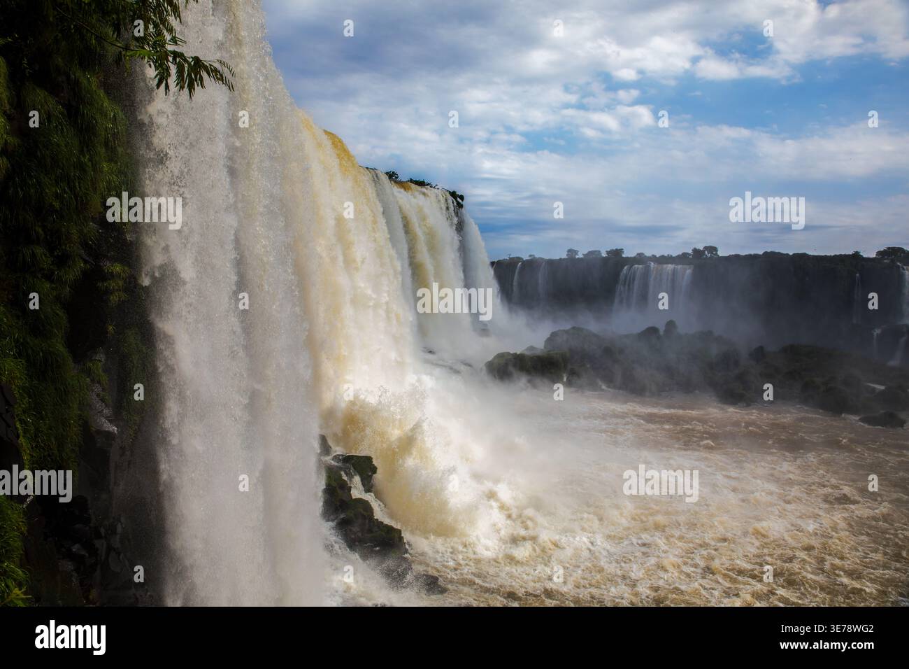 Die mächtigen Iguazu-Fälle donnern mit immenser Kraft in Foz do Iguacu, Parana, Brasilien, und senden enorme Mengen an turbulentem braungefärbtem Wasser Crashin Stockfoto