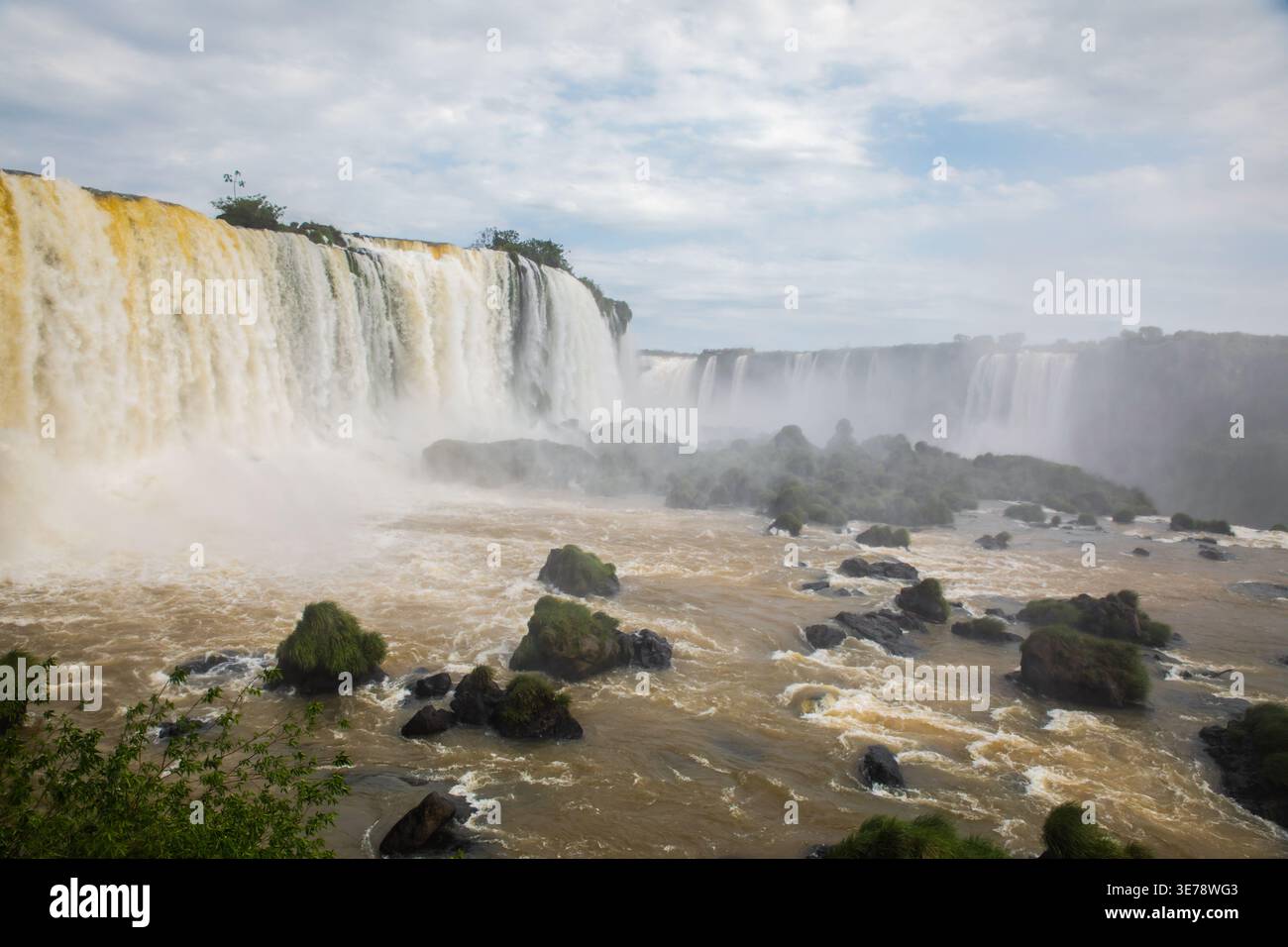 Die herrlichen Iguazu-Fälle donnern entlang eines breiten, geschwungenen Steilhangs und senden riesige Vorhänge aus weißem Wasser, die in das turbulente Sediment-la stürzen Stockfoto