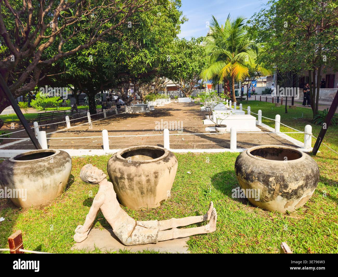 Tuol Sleng Genocide Museum, Phnom Penh, Kambodscha Innenhof, große Wasserkrüge oder thailändische Wasserkrüge, wurden von den Roten Khmer für Folter verwendet, speziell für Wasserboardgefangene. Die Skulptur im Vordergrund ist Teil der Ausstellungen des Museums, die die Gräueltaten an diesem Ort beschreiben. Stockfoto