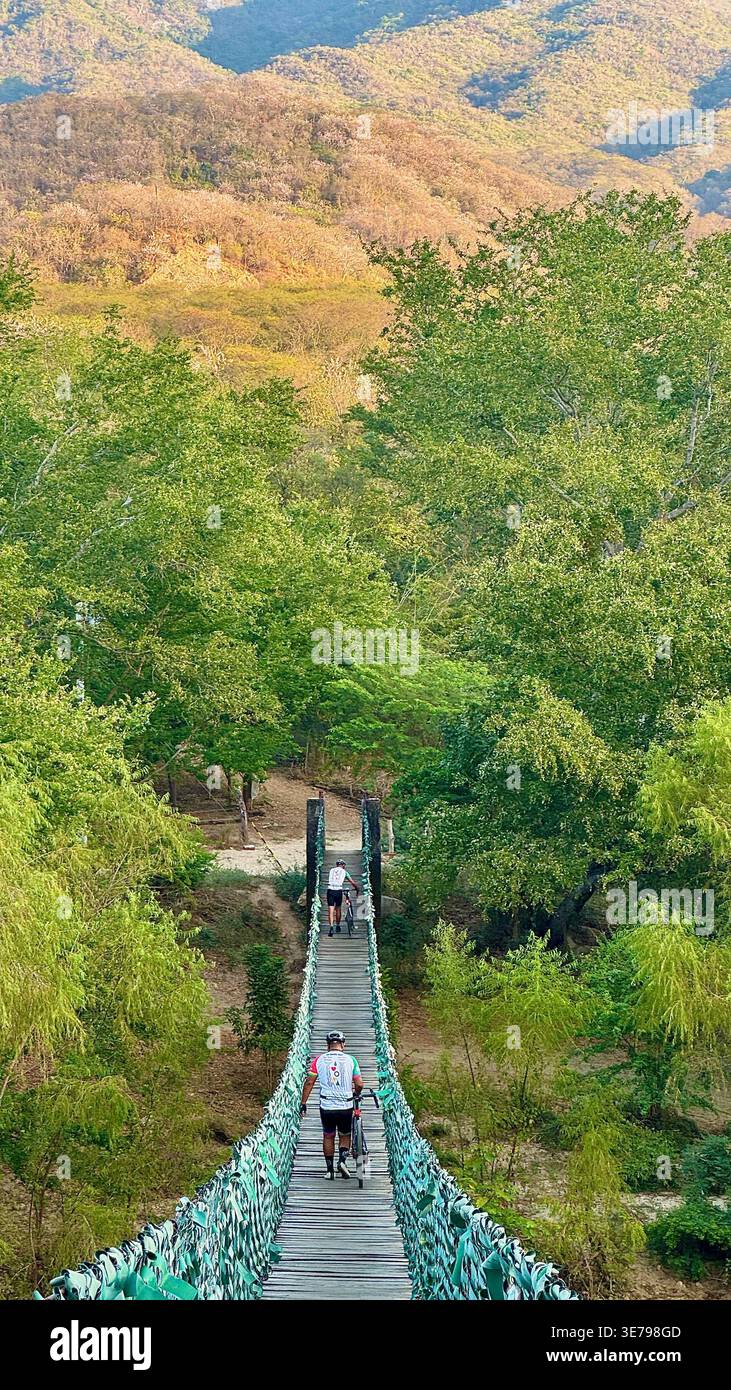 Schwingende Brücke über den Fluss Colotepec mit Mountainbikern - Smartphone-aufgenommenes Stockfoto