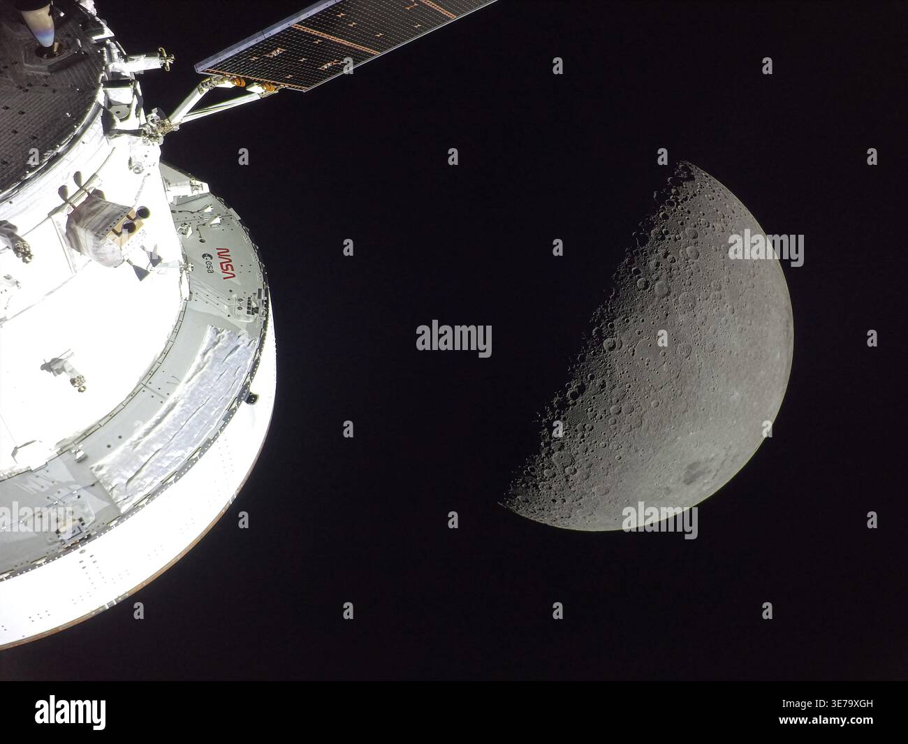 DER MOND, DIE ERDE – 6. April 2026 – die Orion-Raumsonde der NASA ist im Vordergrund zu sehen und wird von der Sonne beleuchtet. Hinter ihm ist ein Mond des ersten Viertels zu sehen, von rechts kommt Sonnenlicht. Am unteren rechten Rand des Mondes hebt sich das Orientale Becken mit einem schwarzen Fleck aus alter Lava in seiner Mitte hervor. Der Orientale ist ein 600 km breiter Einschlagskrater, der von Bergen umringt wird und sich über die nahe und ferne Seite des Mondes erstreckt - Foto: Geopix/NASA Stockfoto