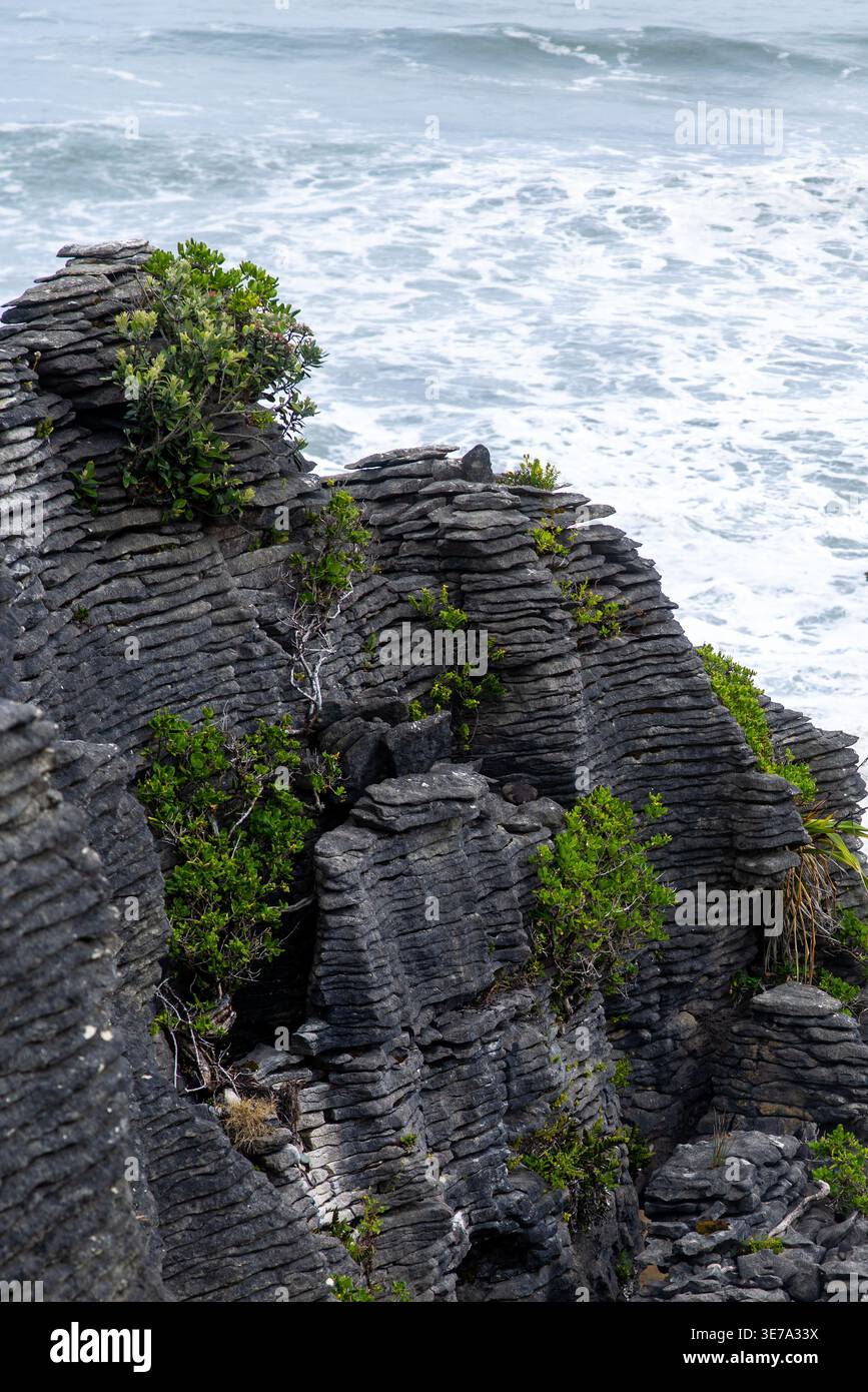Der Blick auf die schroffen Pancake Rocks erhebt sich dramatisch gegen das turbulente, schaumige Meereswasser und zeigt die rohe Kraft der Natur, Pancake Rocks und BloWho Stockfoto