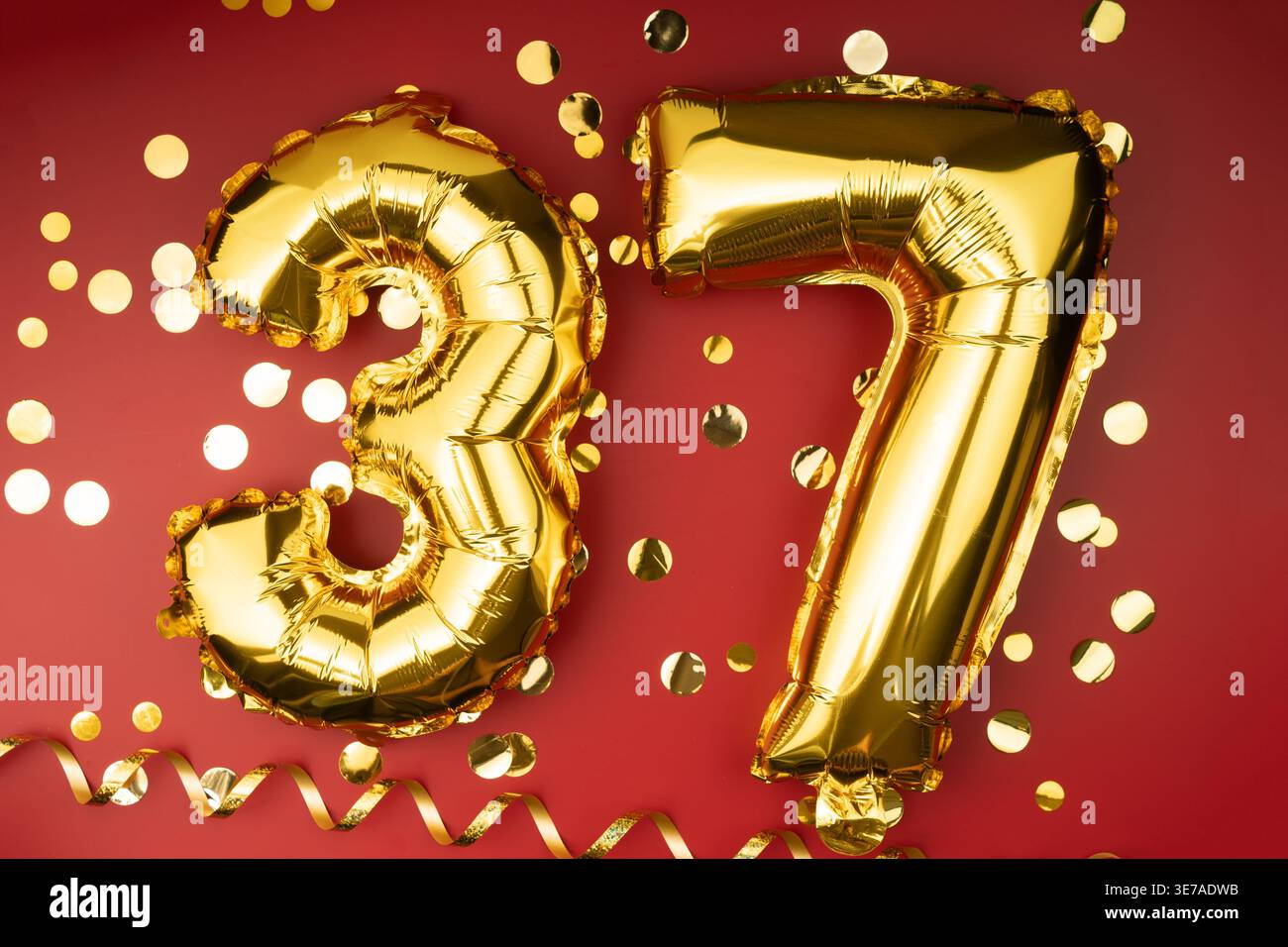 37. Geburtstag. Goldene festliche Ballons Zahl 37-jähriges Jubiläum auf rotem Hintergrund mit Konfetti. Geburtstag oder Hochzeit. Stockfoto
