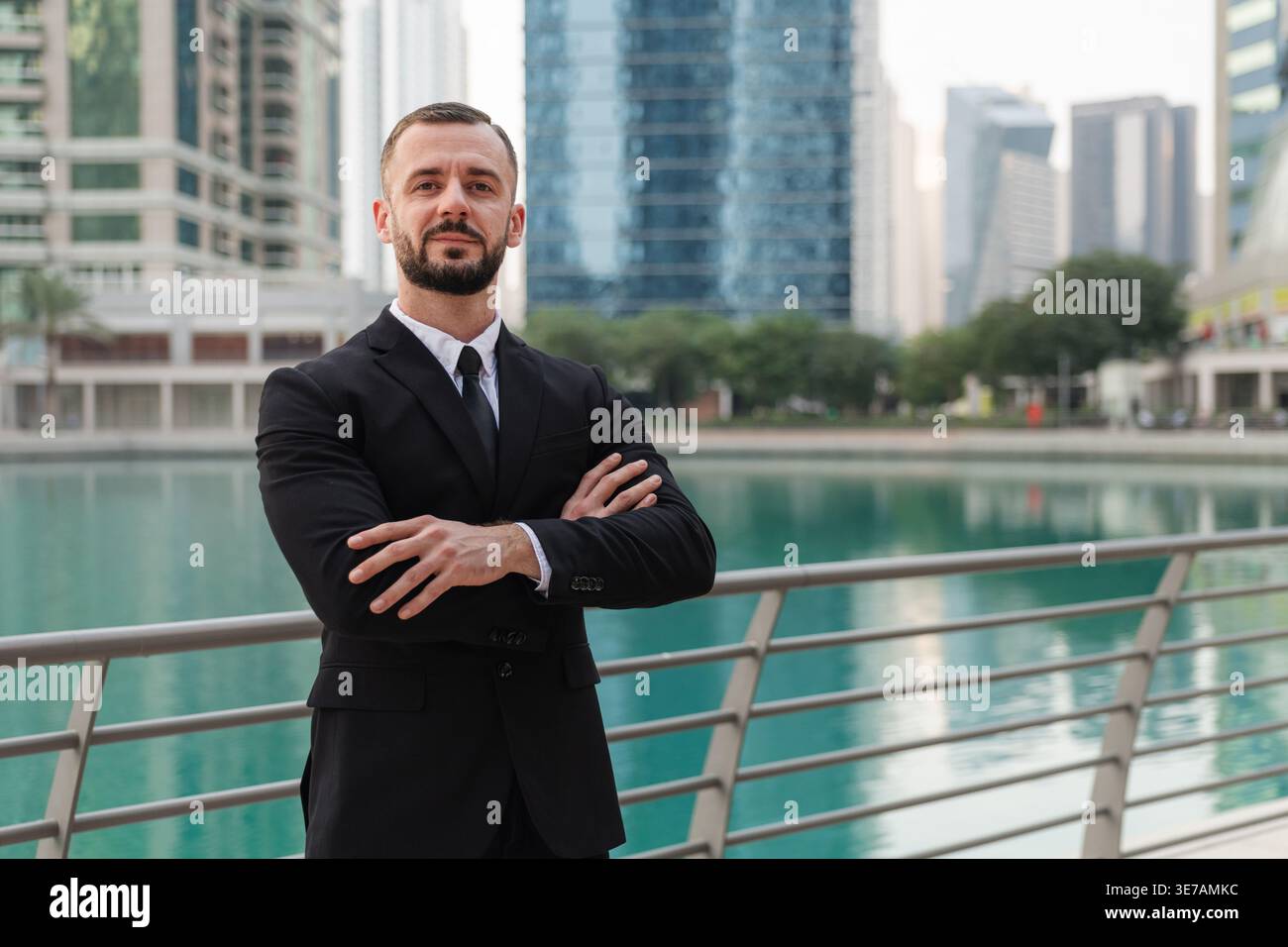 Ein Geschäftsmann in formellem Anzug steht selbstbewusst an der Dubai Marina und zeigt das moderne Berufsleben. Stockfoto