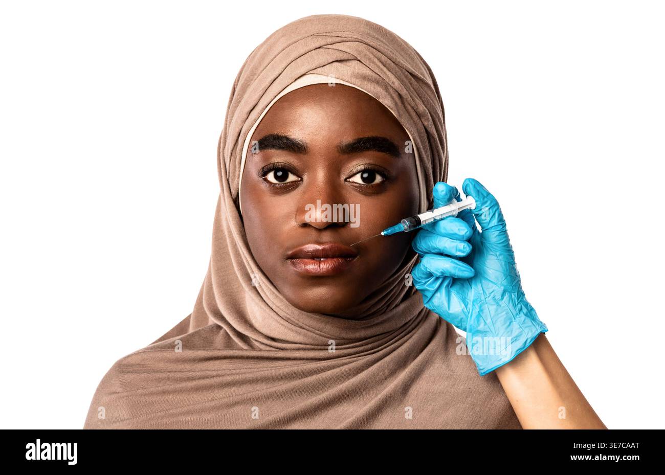 Ernsthafte schwarze muslimische Frau, die Hijab trägt und vom Arzt behandelt wird, während sie vor weißem Hintergrund im Studio steht Stockfoto