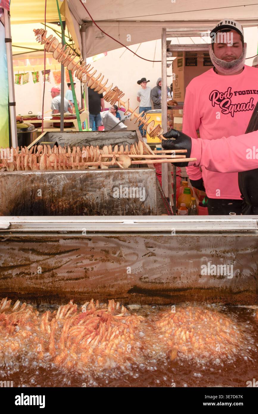 Lebensmittelverkäufer, der Spiralkartoffeln und Zwiebeln beim Texas Onion fest 2026 frittiert, bei dem die süße Zwiebel 1015 gefeiert wird, in Weslaco, Texas, USA. Stockfoto