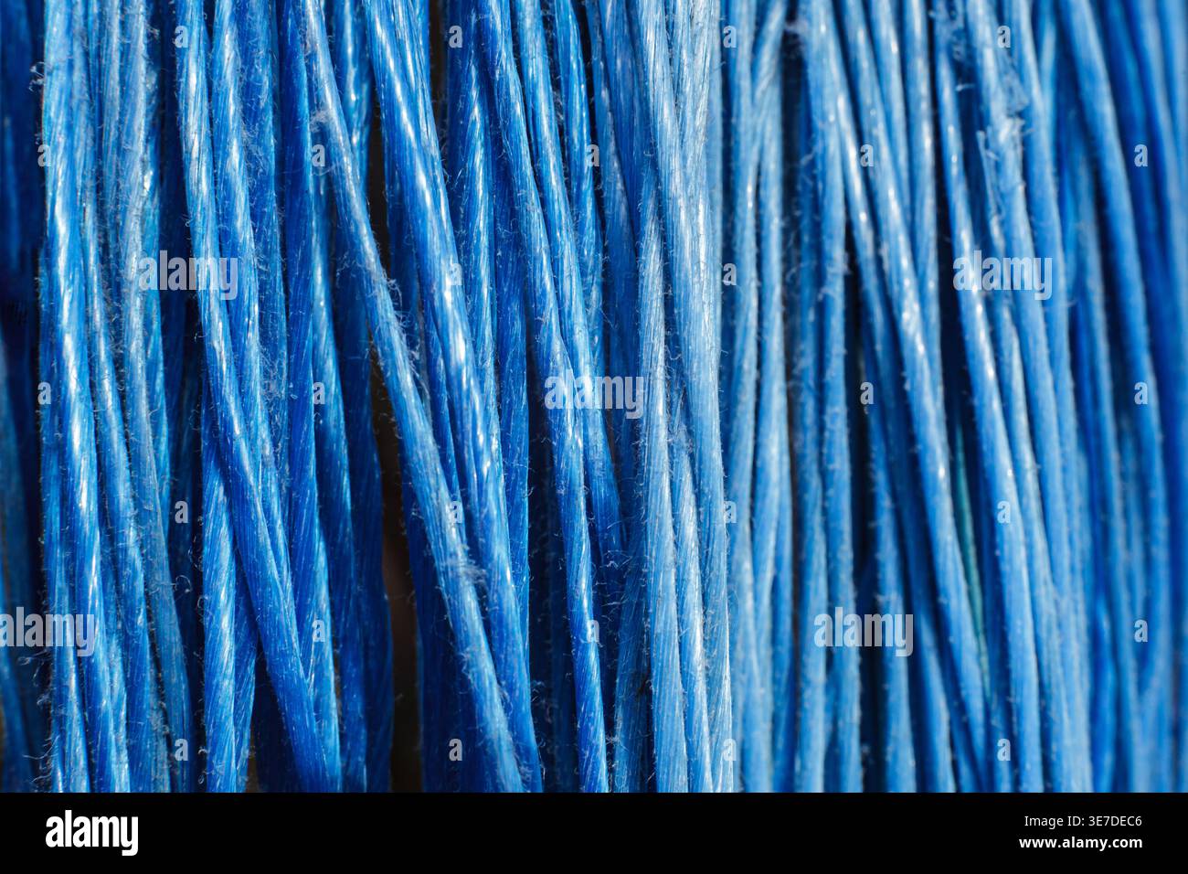 Makroaufnahme aus hellblauen synthetischen Borsten oder Textilfäden, die ein rhythmisches lineares Muster erzeugen. Minimalistischer Hintergrund mit Kopierraum und vertikaler Bildfläche Stockfoto
