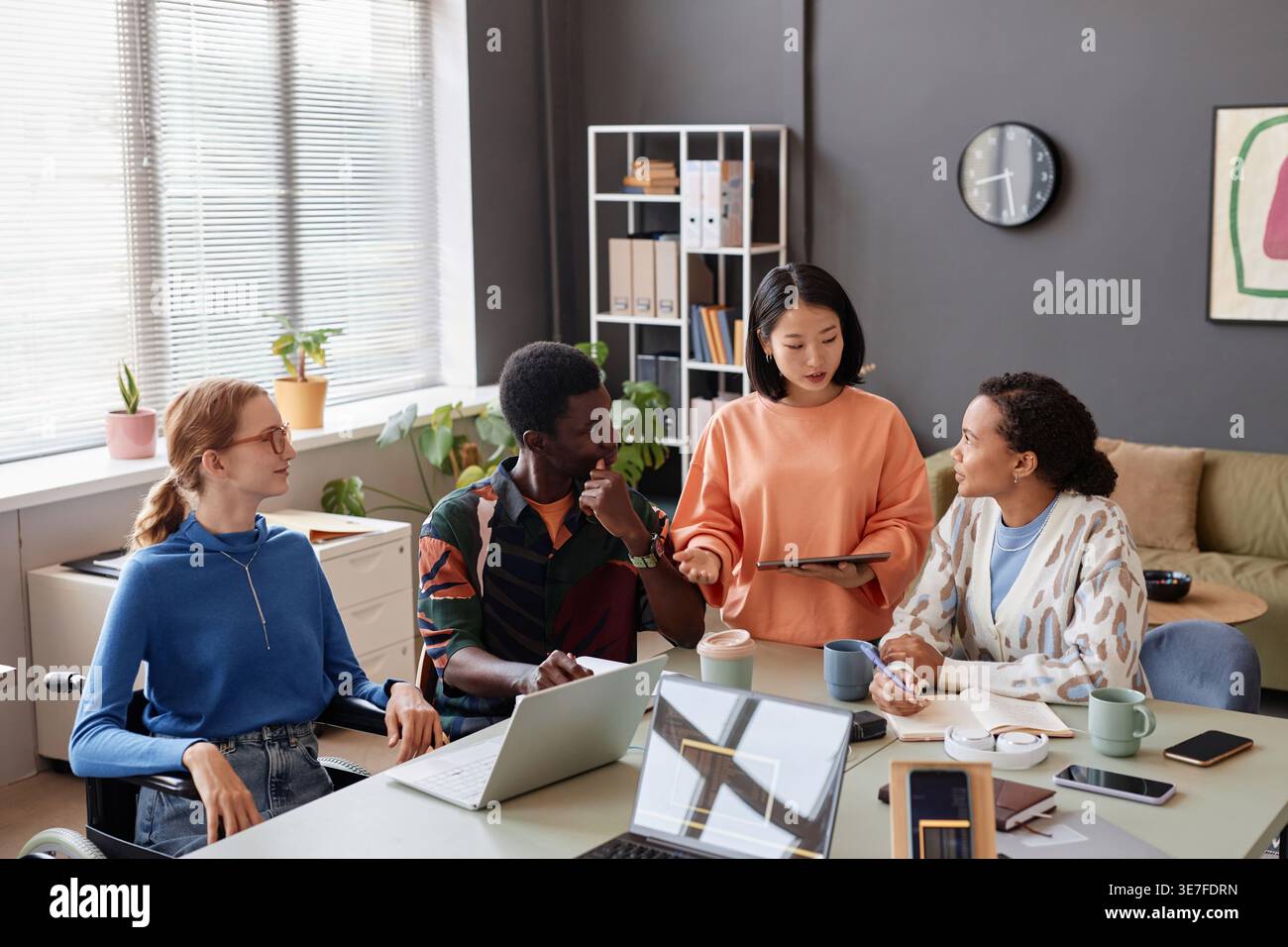 Verschiedene Geschäftsleute diskutieren im Büro über die Arbeit am Tablet Stockfoto
