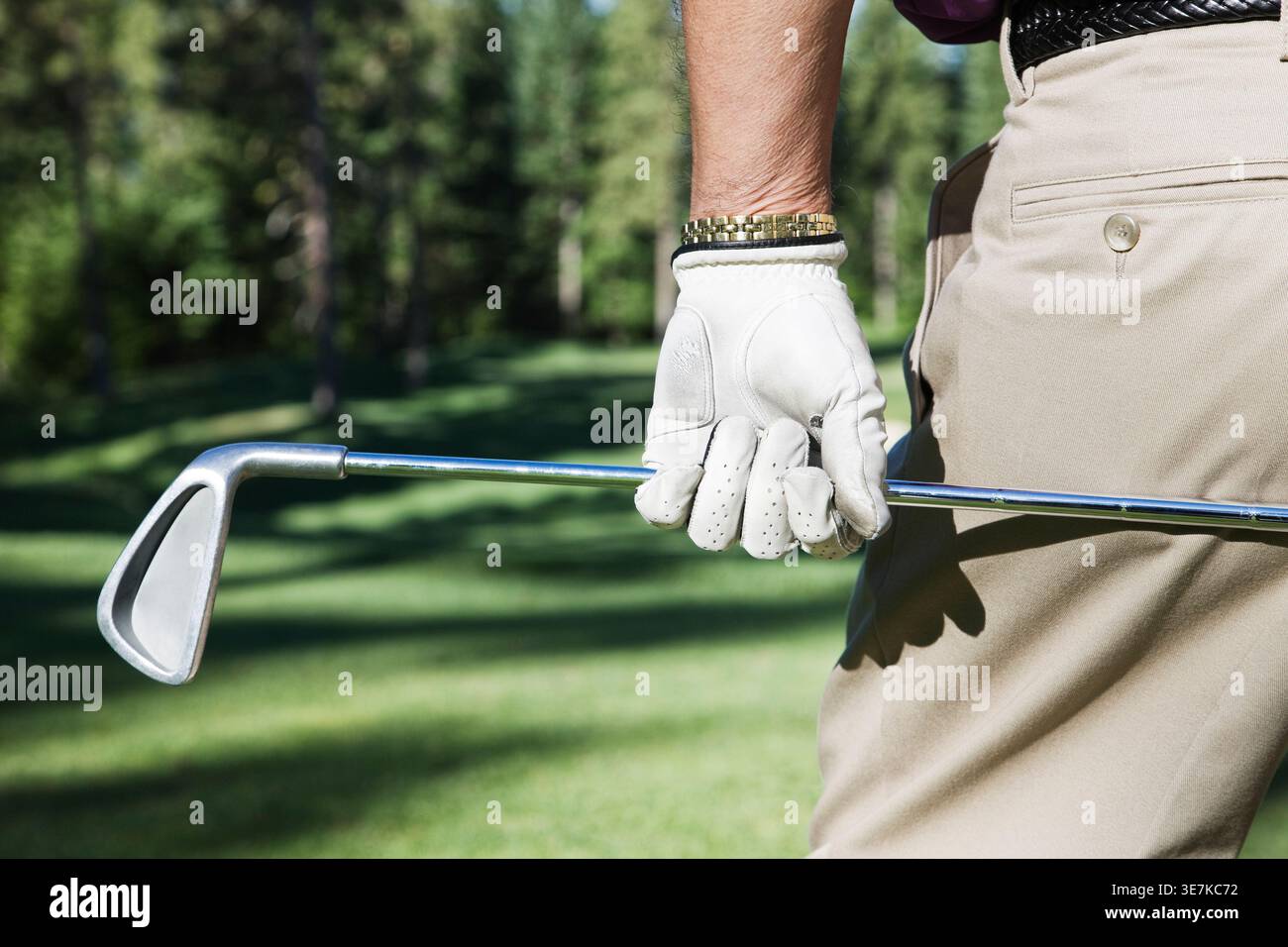 Senior männlicher Golfspieler, der einen Golfschläger hält, der auf einem Golfplatz steht Stockfoto