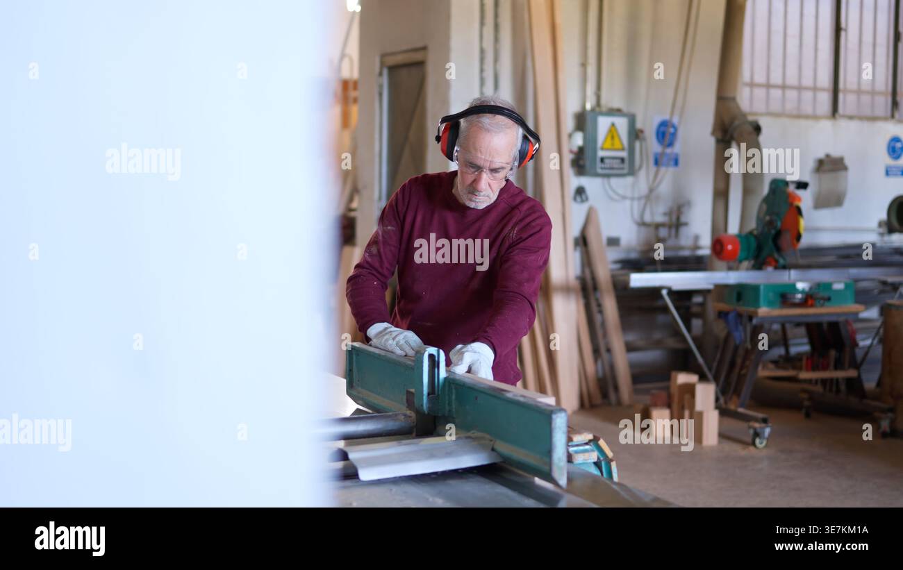 Leitender Zimmermann, der eine Hobelmaschine mit Holzdielen in der Werkstatt arbeitet Stockfoto