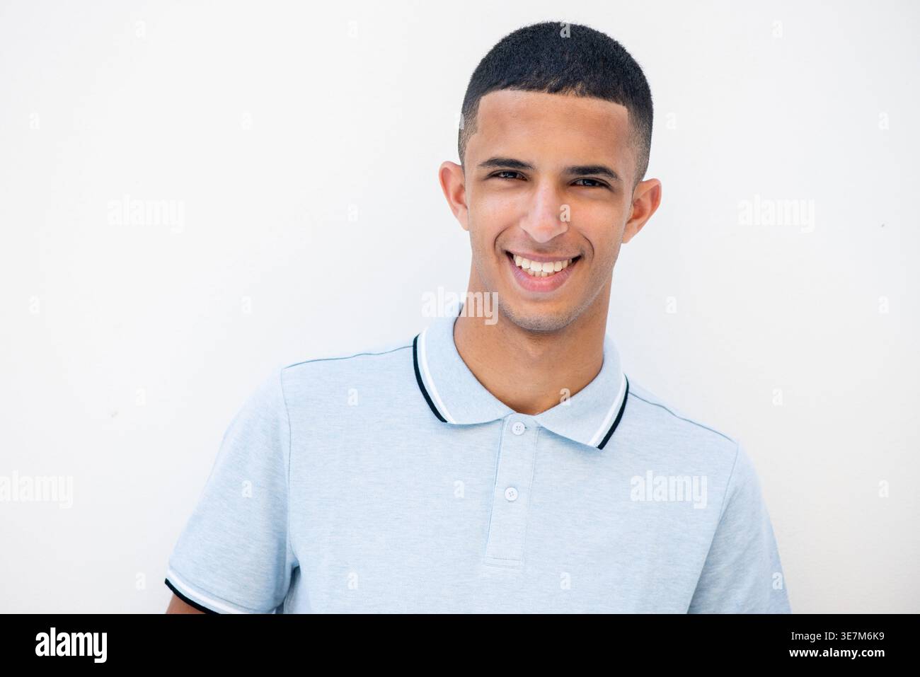 Lächelnder arabischer männlicher Teenager, der vor weißem Hintergrund steht Stockfoto