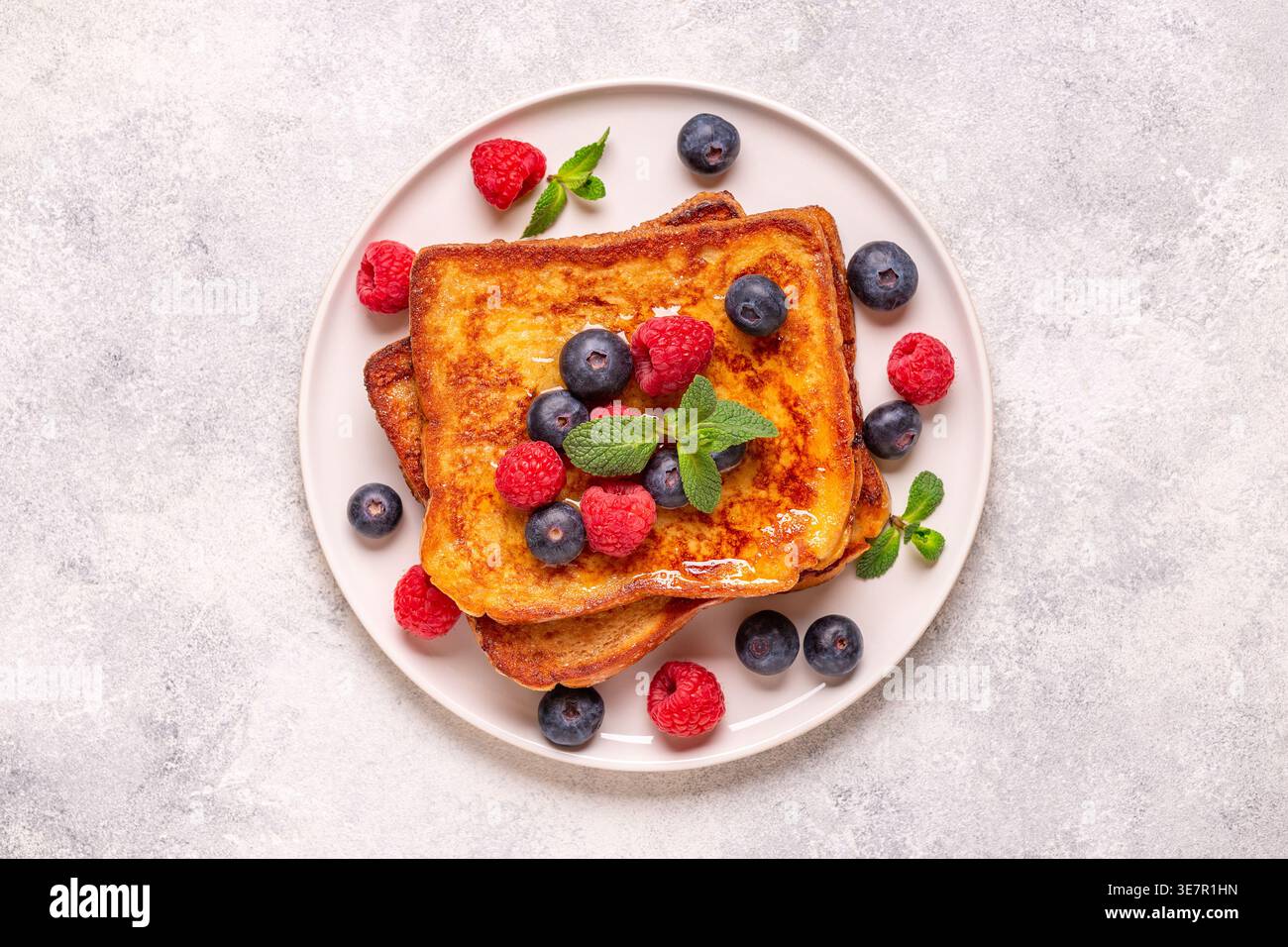Französischer Toast mit Heidelbeeren, Himbeeren, Ahornsirup, Blick von oben. Stockfoto