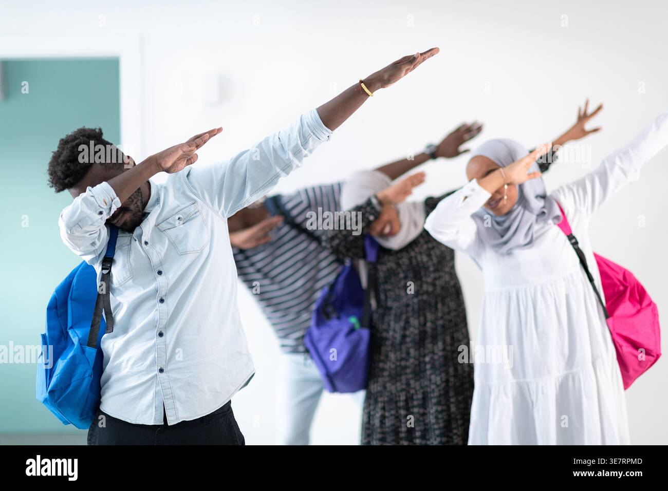 Schwarze und muslimische Studenten, die im Studio mit Rucksäcken vor der weißen Wand stehen Stockfoto