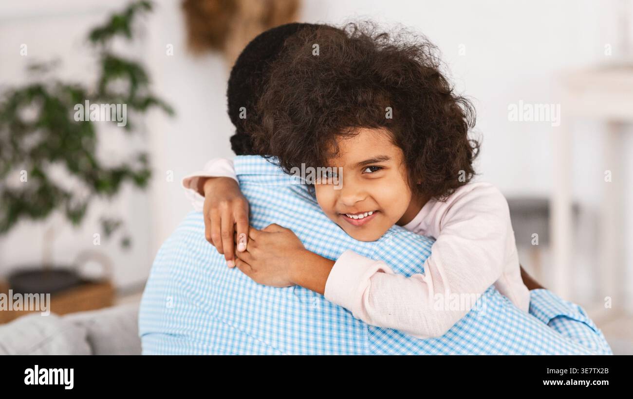 Schwarze Enkelin umarmt Großvater im Wohnzimmer zu Hause Stockfoto