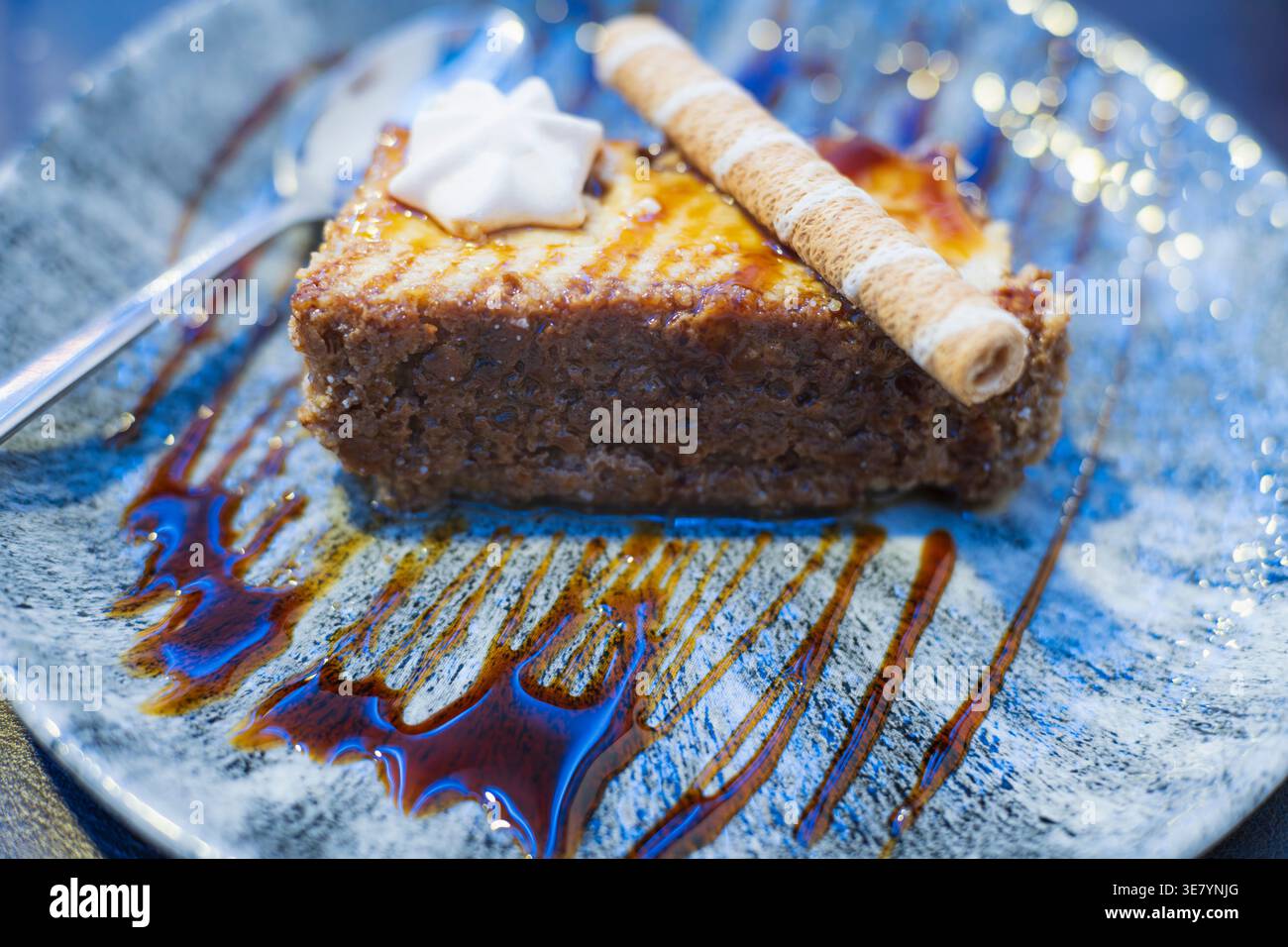 Ein verführerisches Dessert, mit reichhaltiger Karamellsauce und knuspriger Waffel und Schlagsahne, präsentiert auf einem künstlerischen Teller Stockfoto