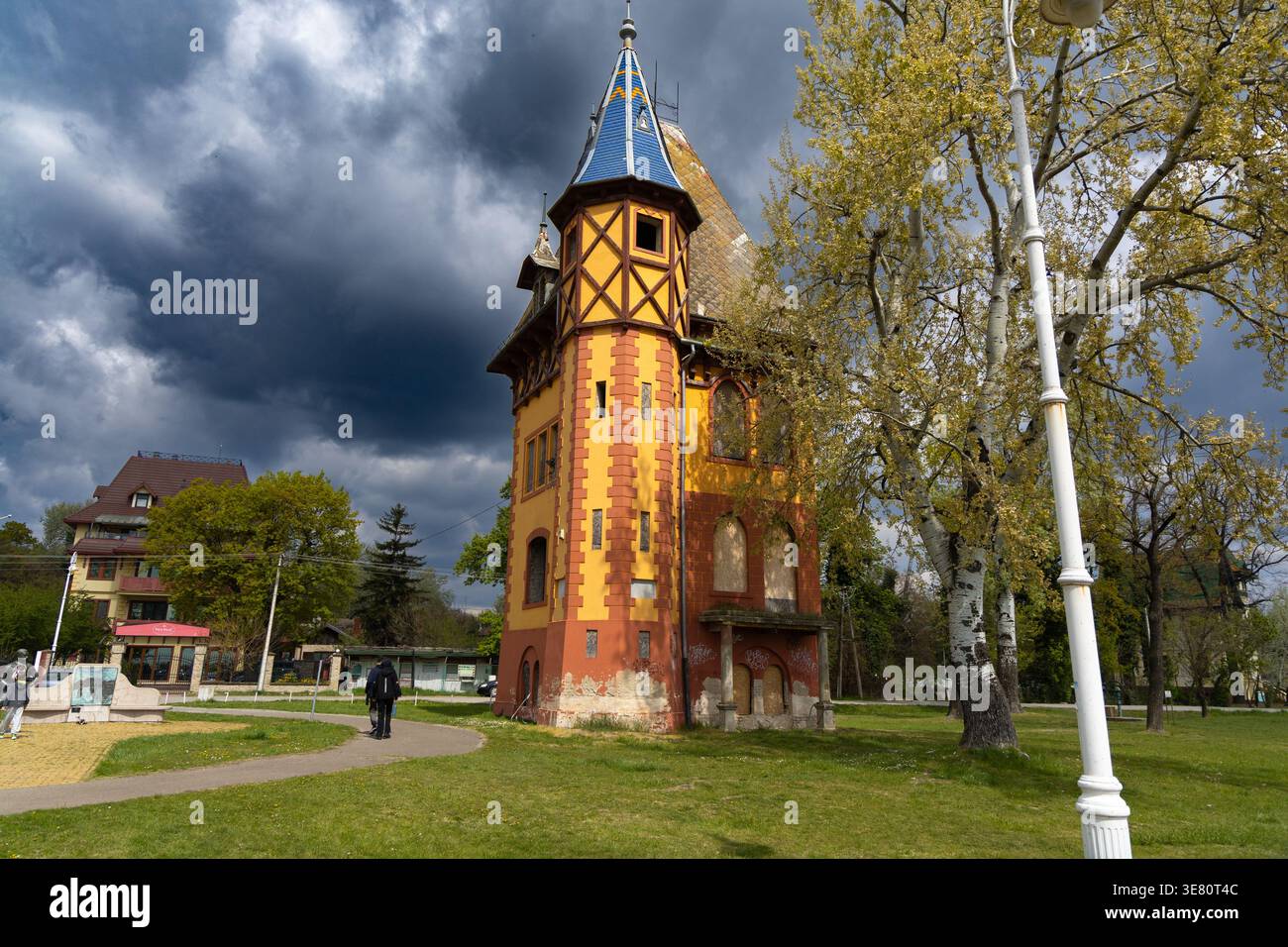 Farbenfroher Historischer Turm Neben Bäumen Unter Stürmischem Himmel Stockfoto
