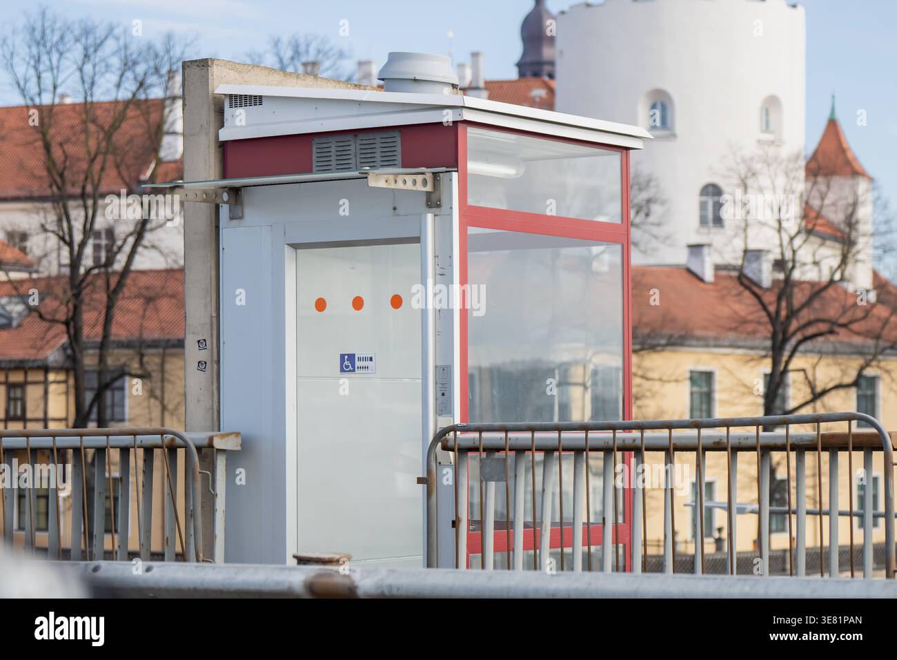 Kleiner Glasaufzug mit Rollstuhlschild neben Brückengeländern und Altstadtarchitektur, Zugang zu öffentlichen Verkehrsmitteln in der Stadt Stockfoto