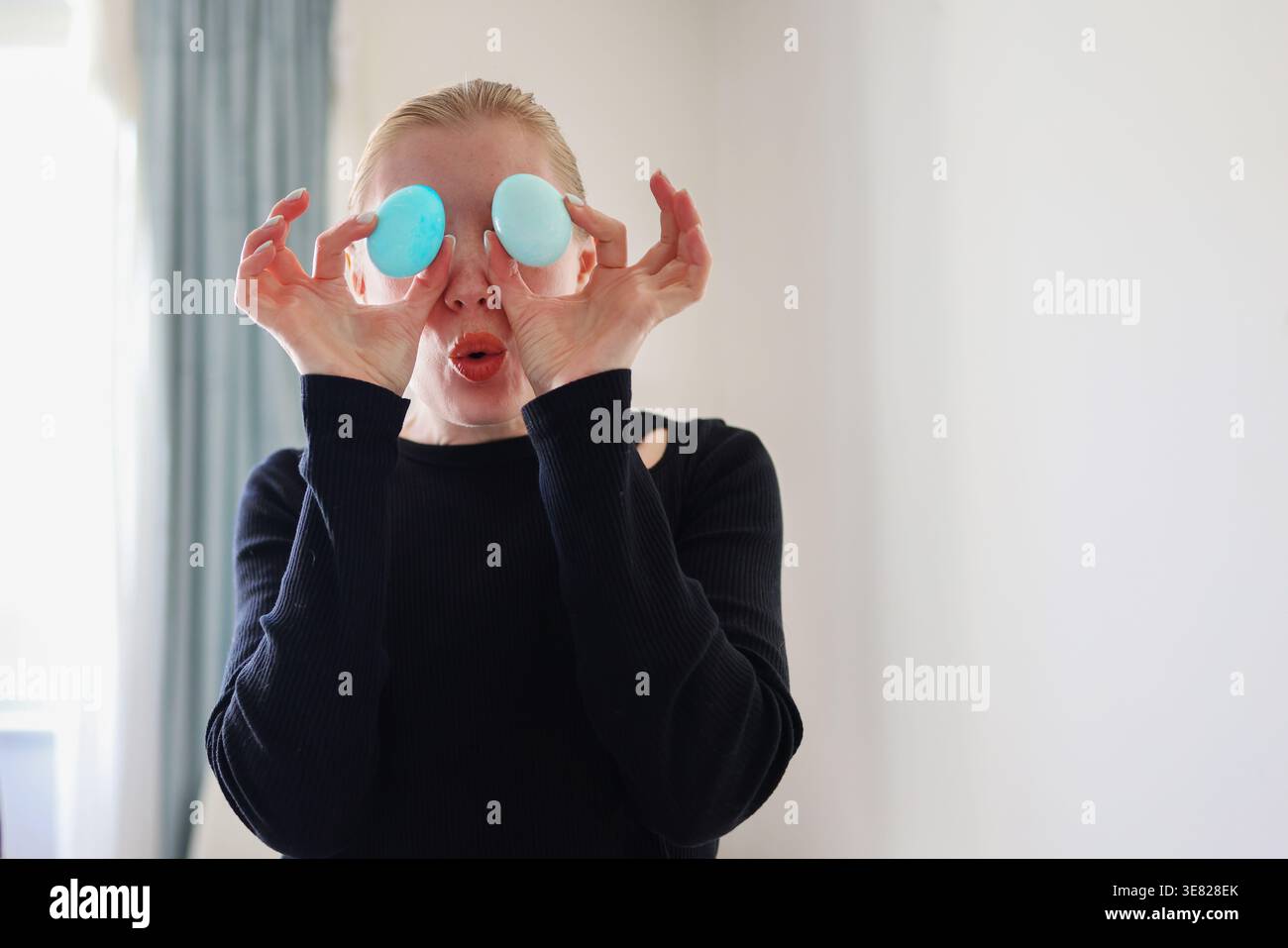 Lustiges Porträt mit gefärbten Eiern, fröhlichem Osterkonzept und kreativer Heimaktivität. Stockfoto