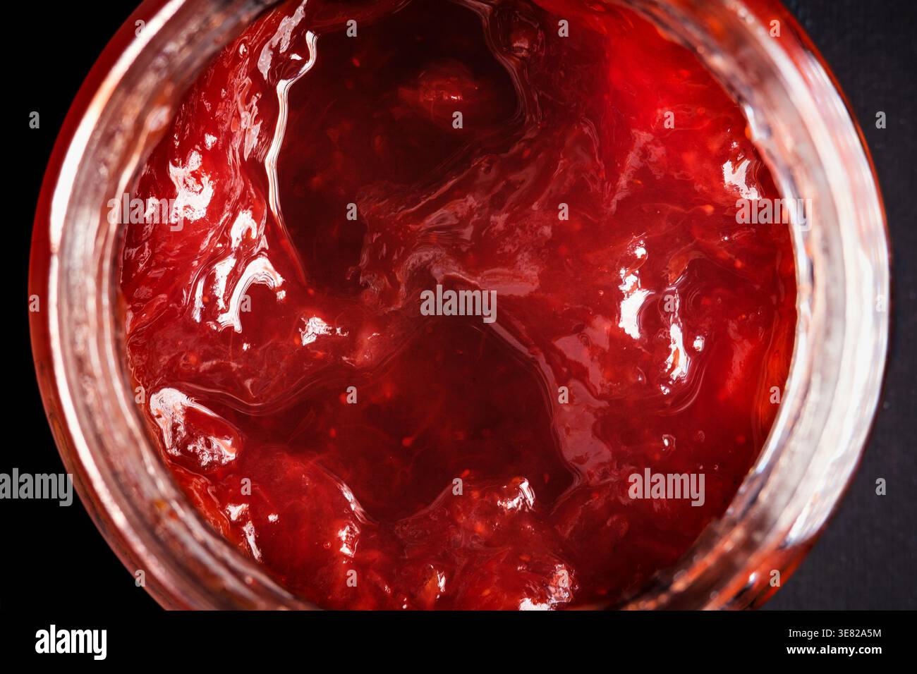 Blick von oben auf Erdbeermarmelade im Glasglas – hausgemachte Textur aus rotem Obst Stockfoto
