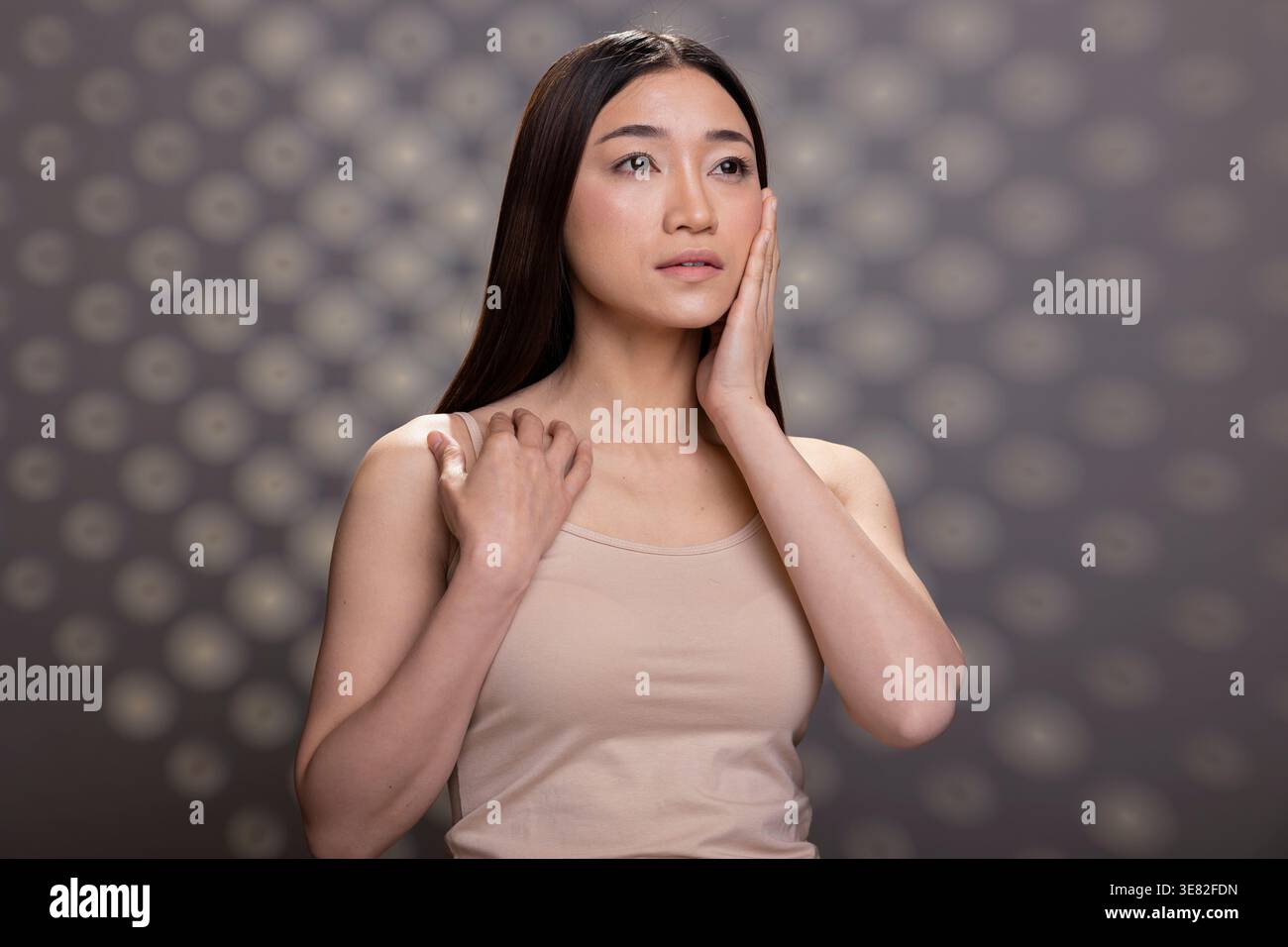 Porträt einer seriösen asiatischen Frau mit glatter Haut und natürlichem Aussehen posiert für Selbstpflegewerbung. Lebendige positive Hautpflege-Darstellung und feminine Empowerment im Studio. Stockfoto