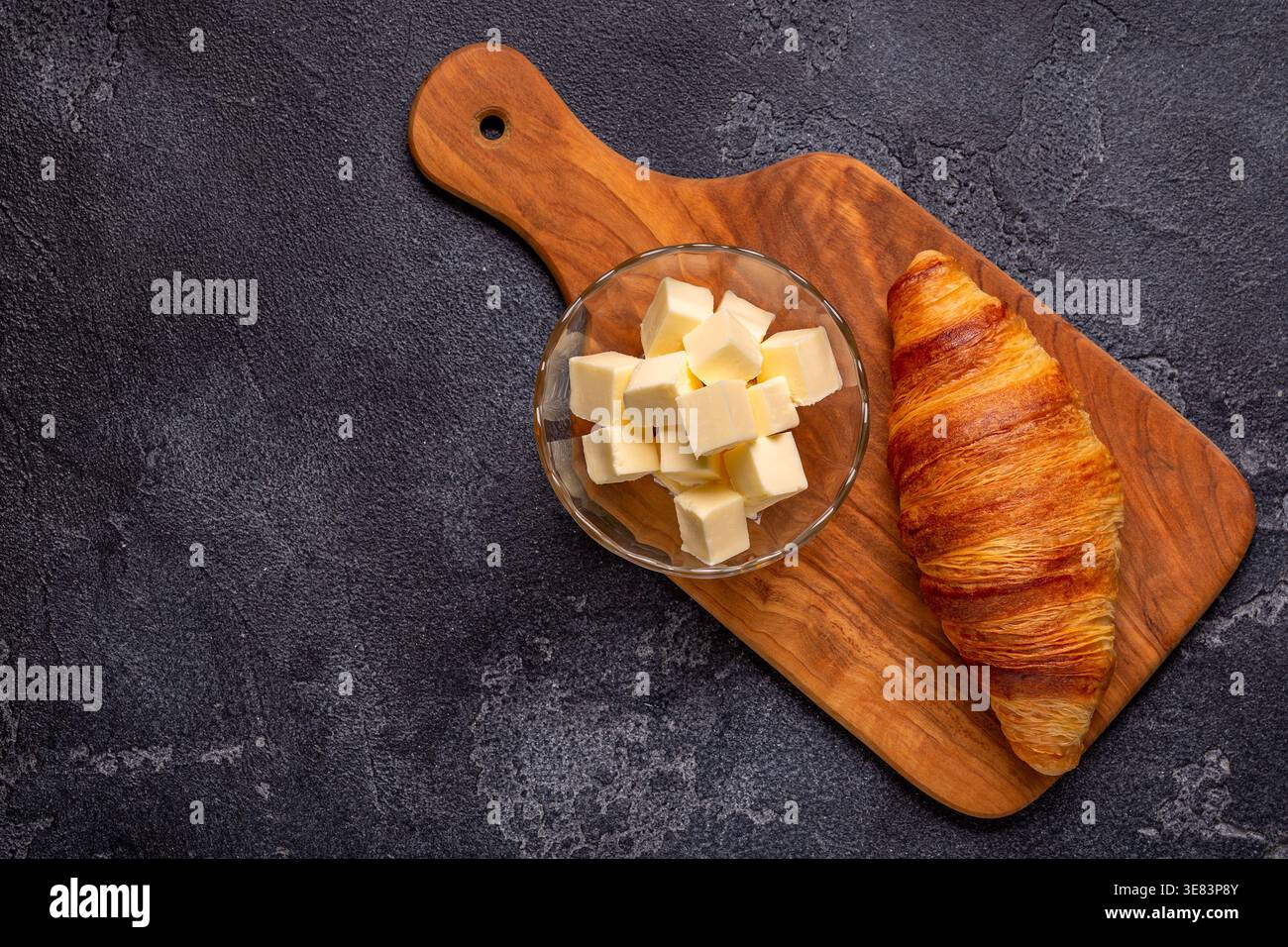 Französisches Croissant. Frisch gebackene Croissants mit Butter auf dunklem Steinhintergrund. Stockfoto