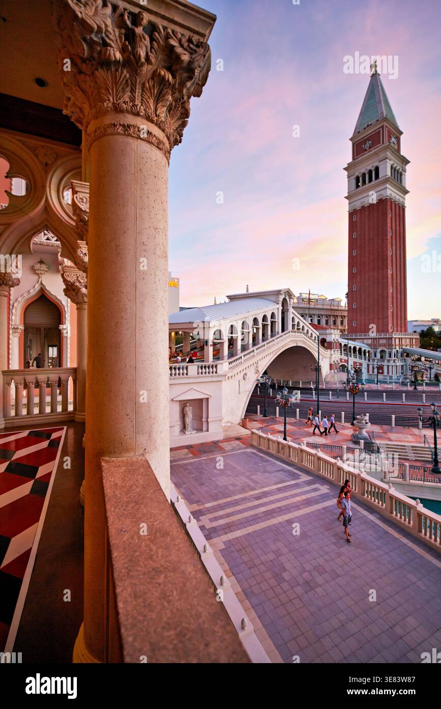 Das Venetian Hotel in Las Vegas zeigt die Farben des Sonnenuntergangs über dem Gebäude und der Brücke. Die Leute laufen in der ruhigen Gegend und genießen die Aussicht. Stockfoto