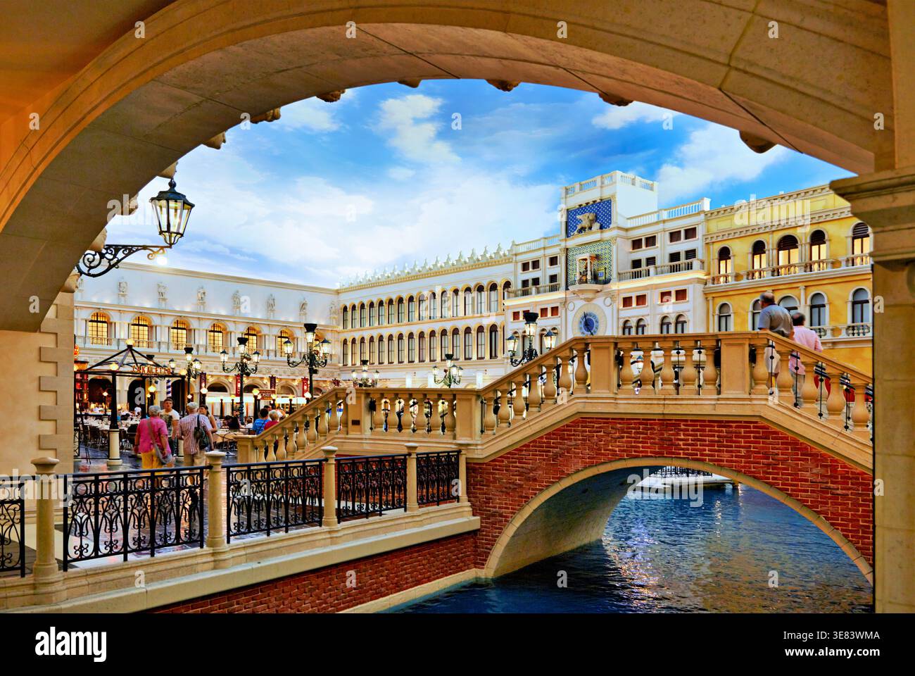 Im Venetian Hotel and Casino in Las Vegas spazieren die Menschen entlang der Brücke in Little Venice. Die Umgebung bietet farbenfrohe Gebäude und Wasser. Stockfoto