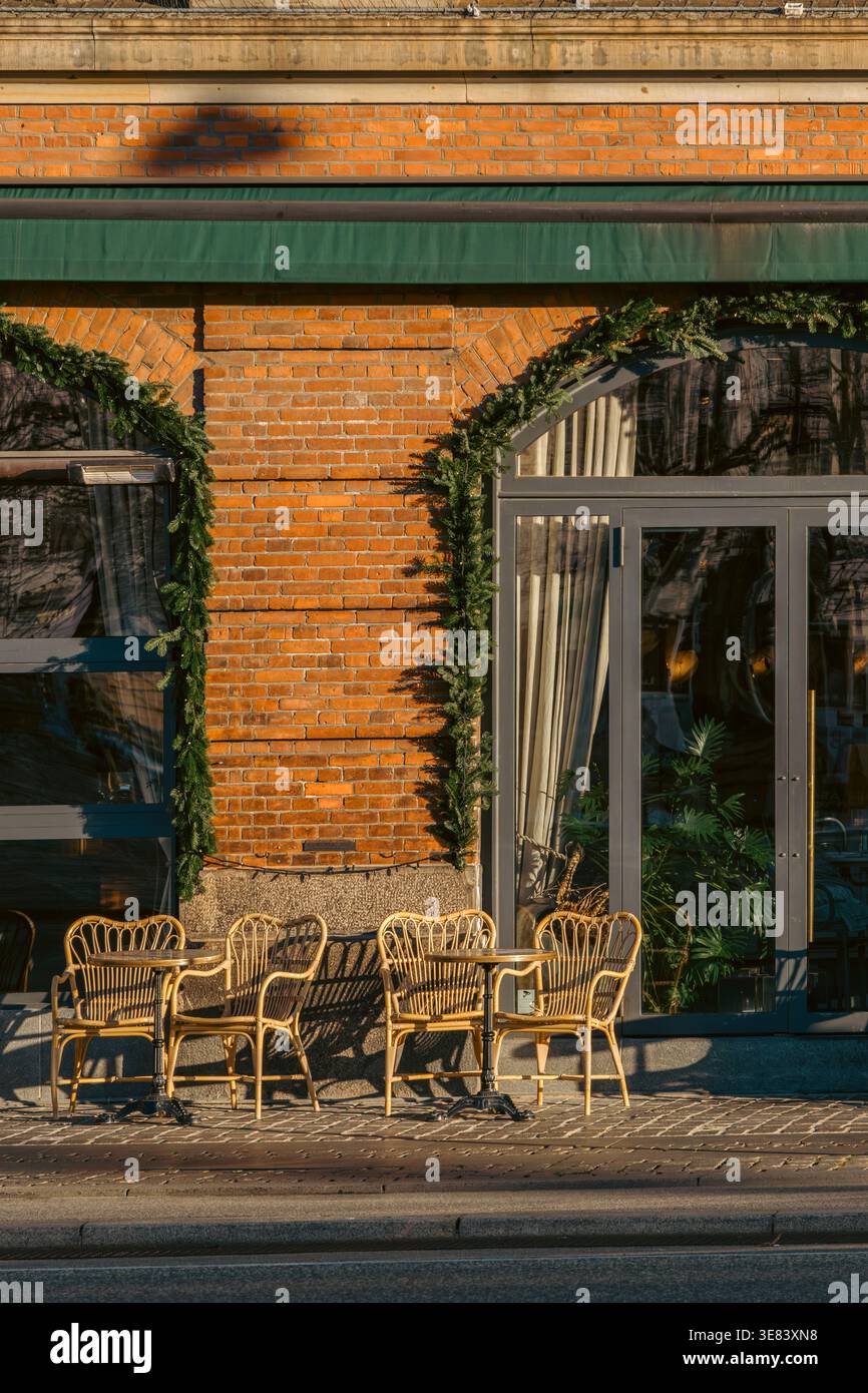 Leere Terrasse im Freien mit eleganten Korbstühlen und Tischen Stockfoto