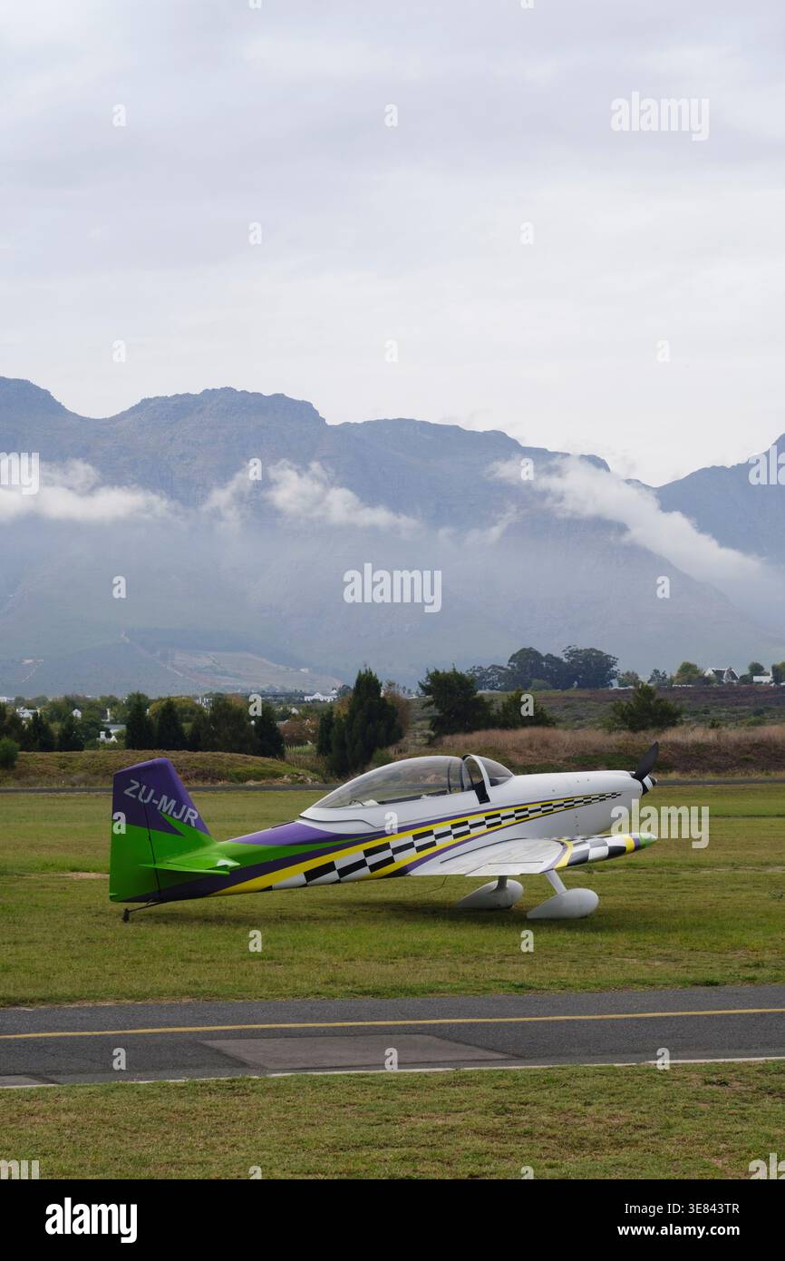 Geerdetes, leichtes Flugzeug mit Bergen im Hintergrund und sichtbaren Wolken im Stellenbosch Flying Club. Stockfoto