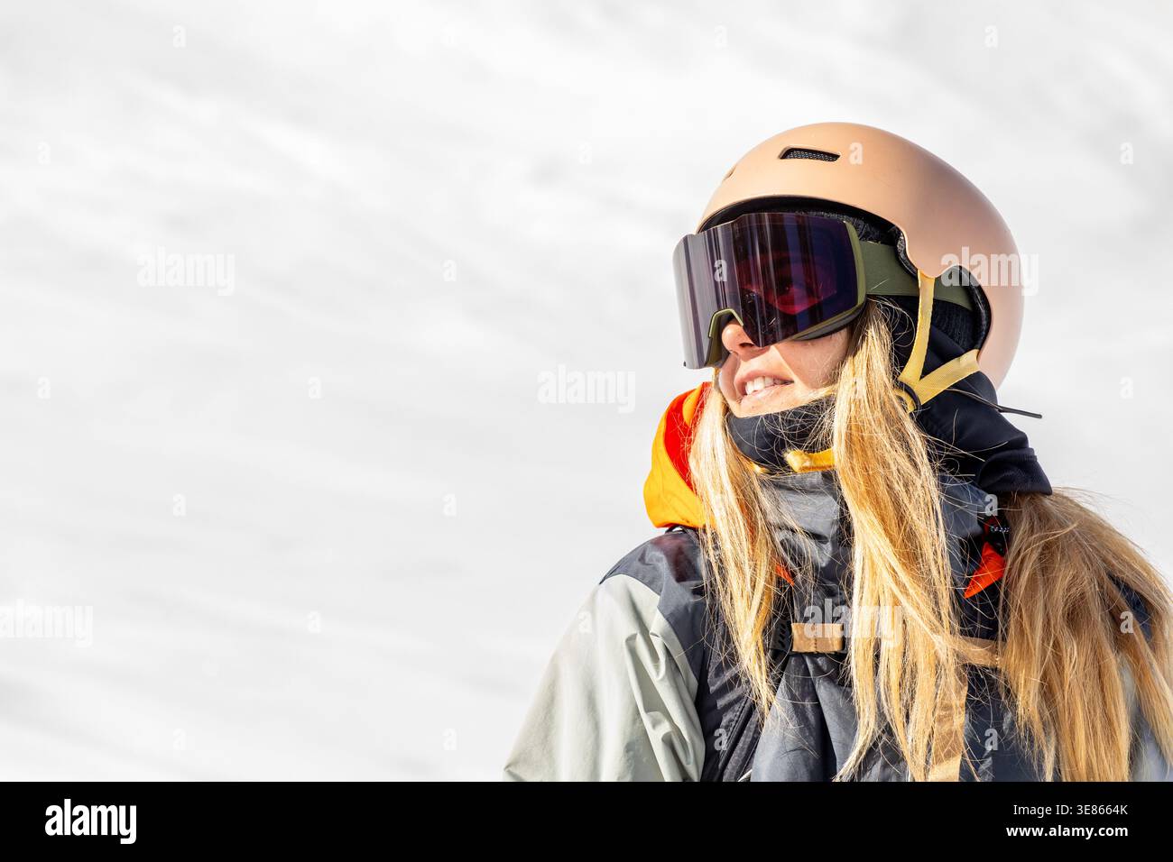 Porträt einer Snowboarderin mit Helm und Schutzbrille, lächelnd im hellen Winterlicht auf einer verschneiten Piste in den Pyrenäen, Outdoor-Sport Stockfoto
