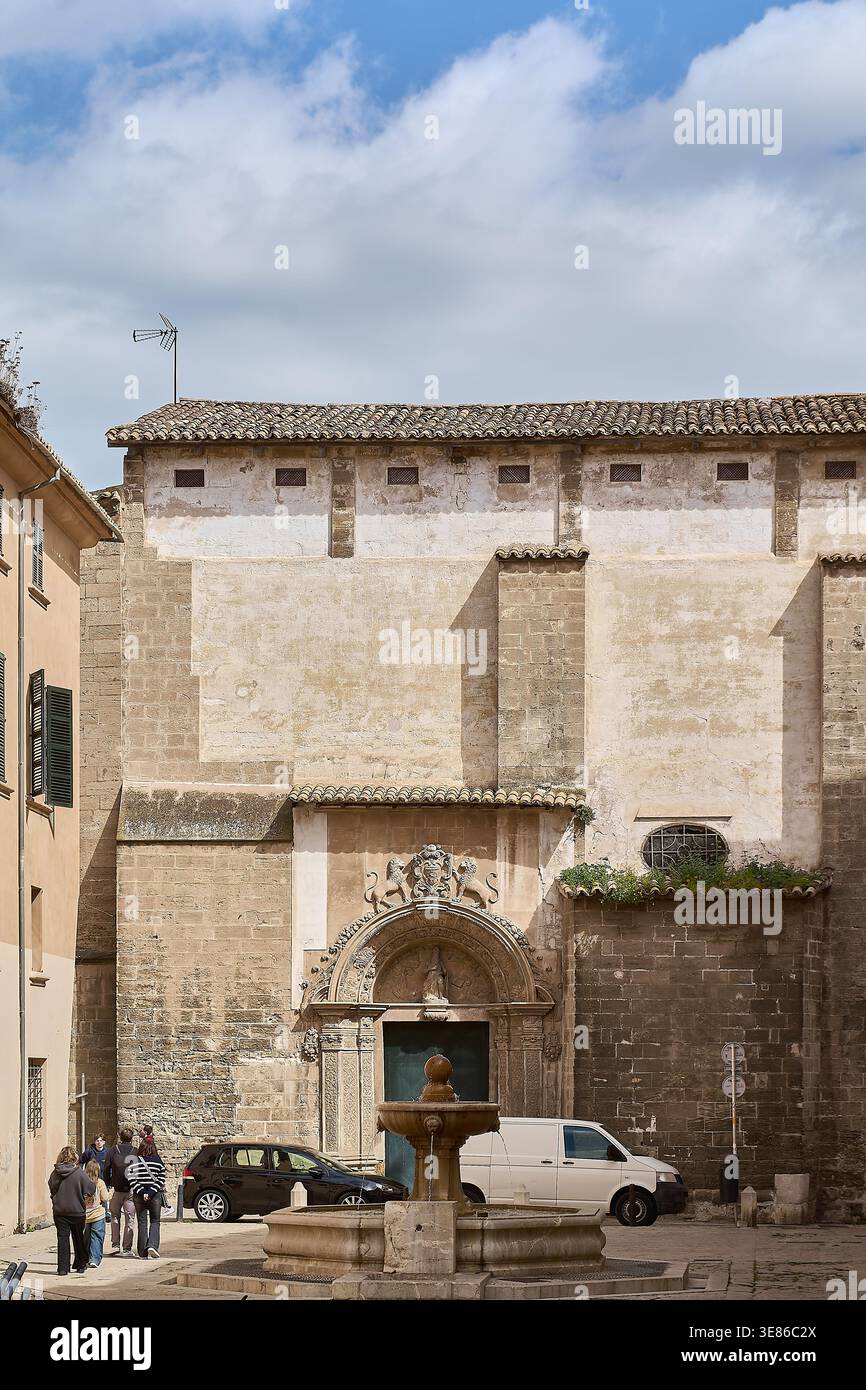Mallorca. Spanien - 12. April 2026: Touristen gehen durch einen historischen mediterranen platz mit dem Steinportal von Esglesia de Sant Jaume und einem c Stockfoto