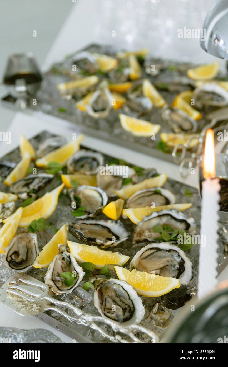Frische Austern serviert auf Eis mit Zitronenscheiben an einem eleganten Empfang mit Meeresfrüchten. Stockfoto