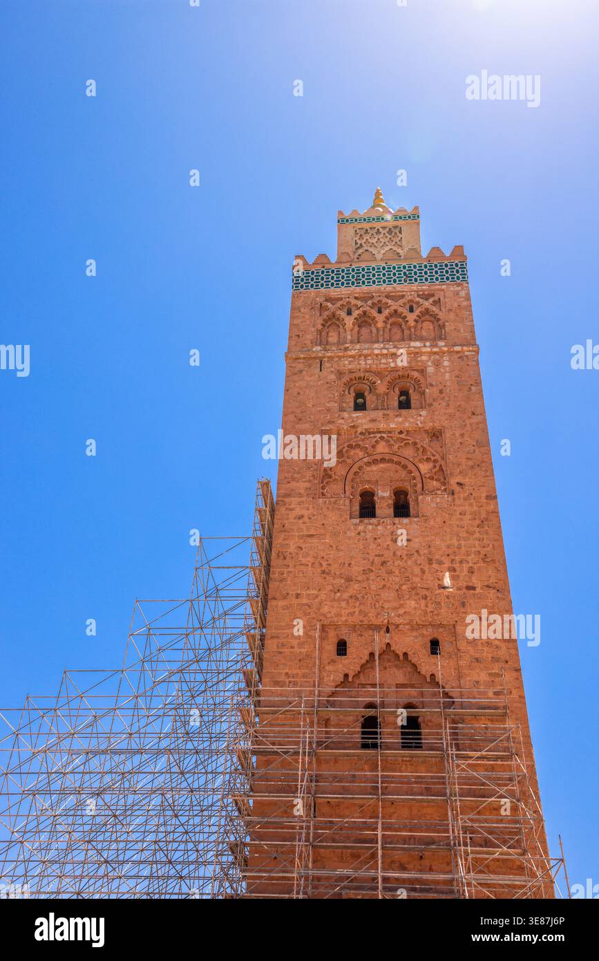 Niedrigwinkelaufnahme des majestätischen Minaretts der Koutoubia-Moschee mit Gerüsten vor tiefblauem Himmel in Marrakesch, Marokko Stockfoto