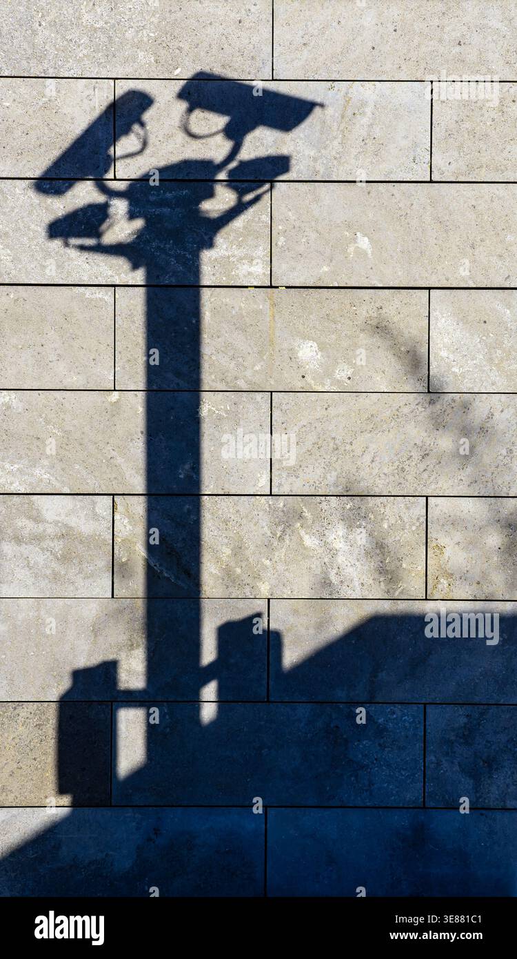 Schatten von Überwachungskameras an einer Wand als Symbol für Überwachung, Sicherheit und Privatsphäre. Konzept, Wand, Hintergrund, Kamera, Schatten vertikal Stockfoto