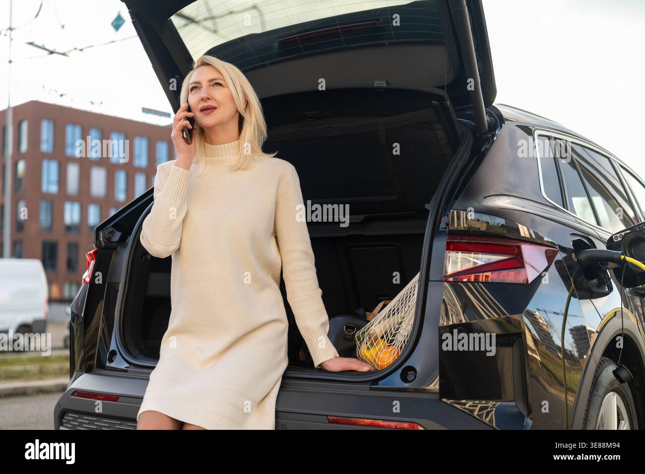 Führen Sie ein Telefongespräch aus dem Fondfach eines schicken SUV, der in einer städtischen Umgebung geparkt ist. Stockfoto