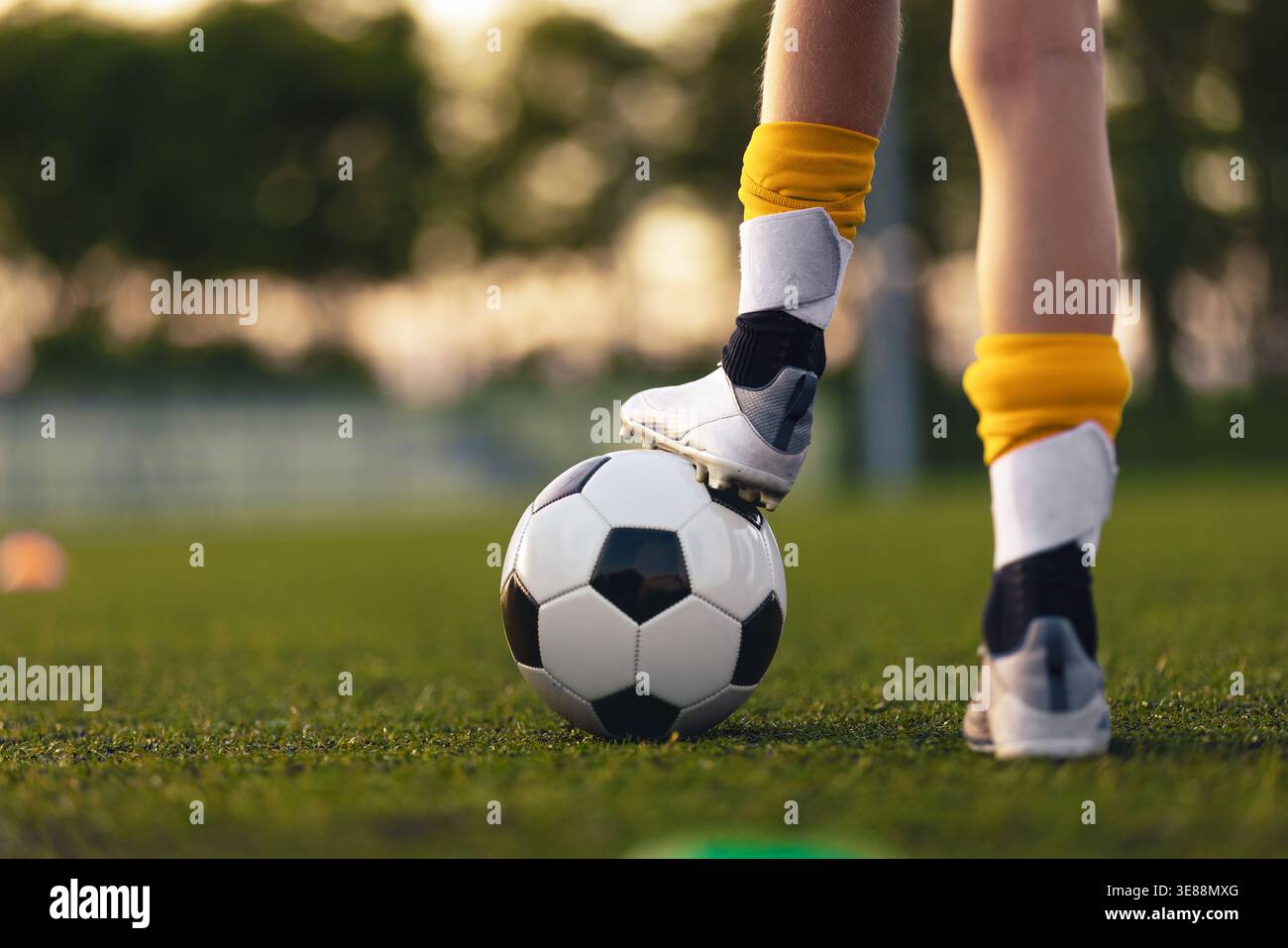 Nahaufnahme Mit Fußball-Kontrolle Für Jugendliche. Das Kind steht während des Trainings auf dem Grasfeld mit Fuß auf dem Fußball Stockfoto