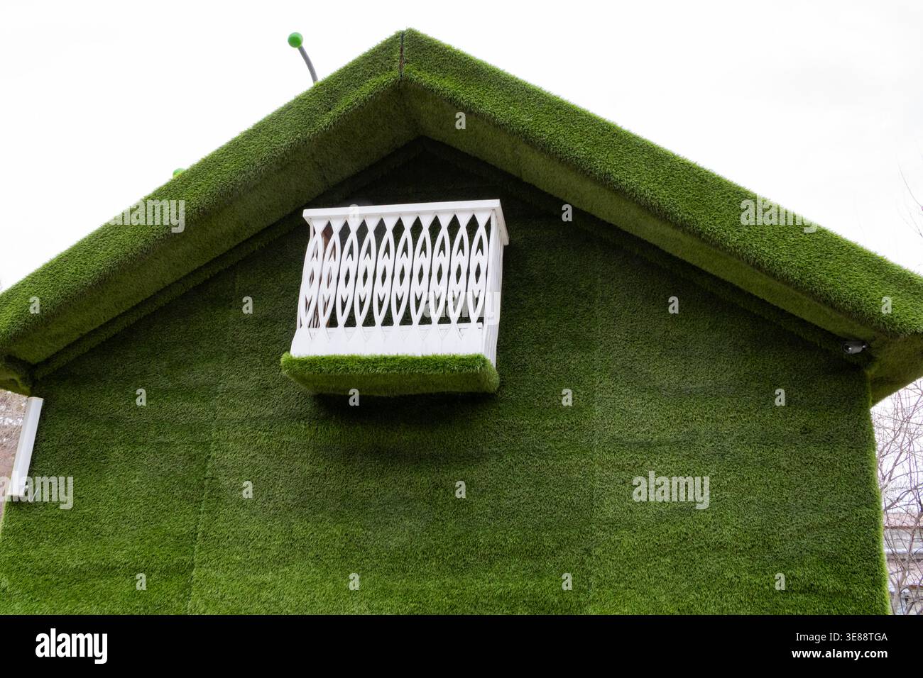 Innovative grüne Architektur: Ein einzigartiges Gebäude mit umweltfreundlichem Design mit Kunstrasen und eleganten weißen Balkondetails Stockfoto