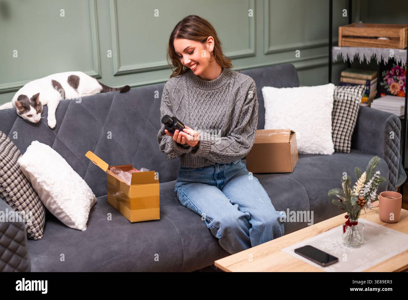 Eine fröhliche Frau, die sich Parfüms ansah, die sie online kaufte und im Paket geliefert wurde. Stockfoto