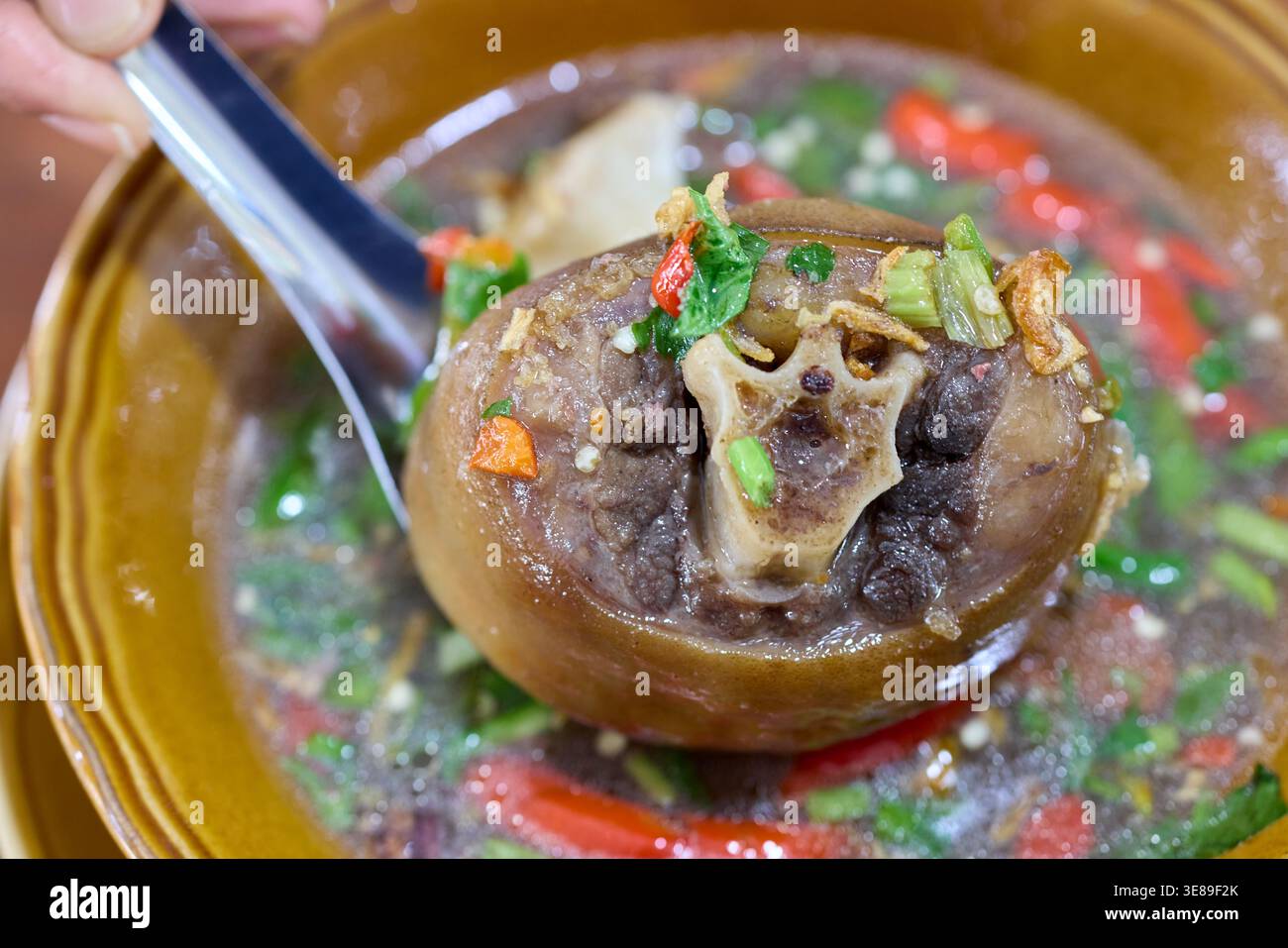 Nahaufnahme einer scharfen Oxtail-Suppe mit Kräutern und Chilis Stockfoto