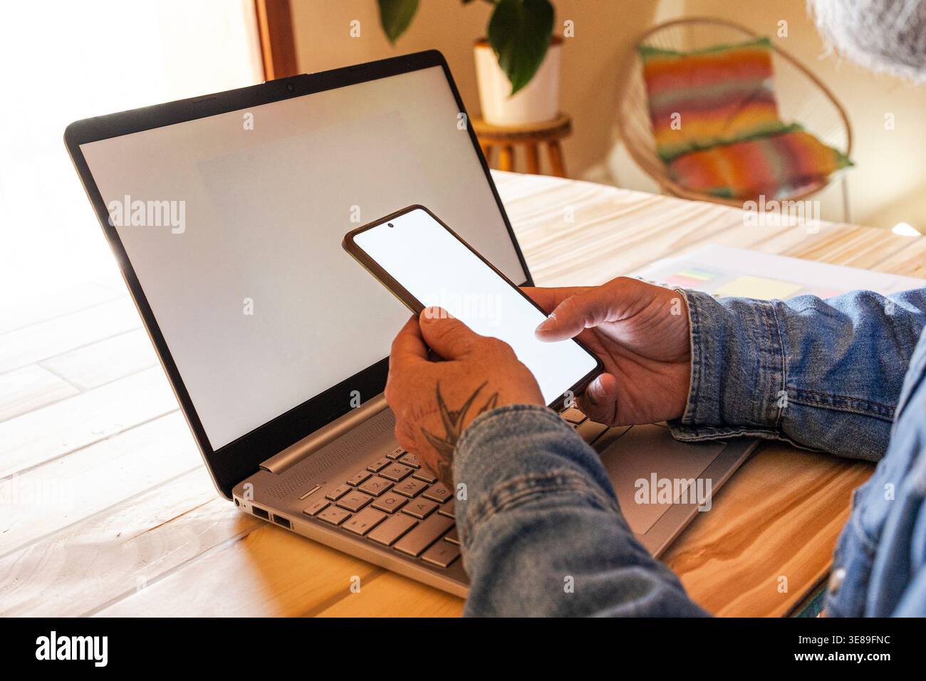 Person, die per Fernzugriff mit Laptop und Mobiltelefon arbeitet Stockfoto