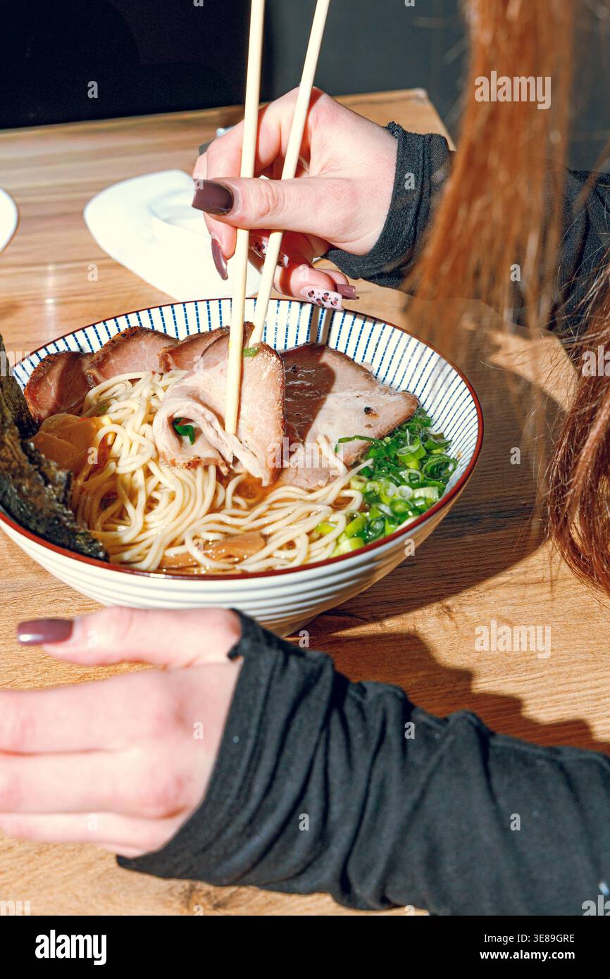 Mann isst Ramen mit Stäbchen. Professionelle Studio-Leuchte Stockfoto