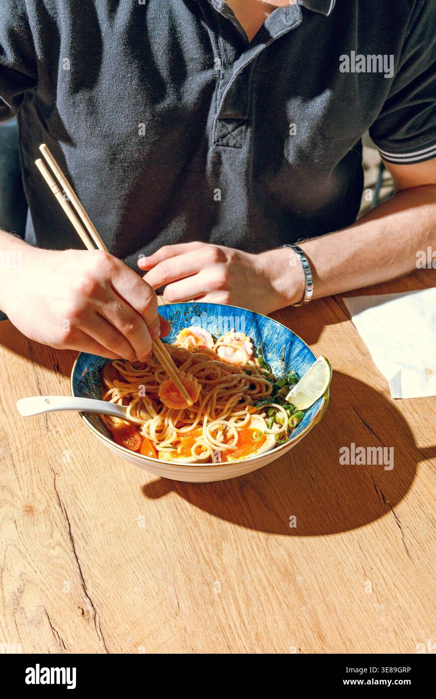Mann isst Ramen mit Stäbchen. Professionelle Studio-Leuchte Stockfoto